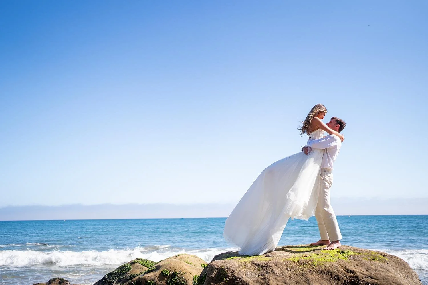Wedding portraits at Malibu Farm at the Pier of groom lifting bride with ocean background