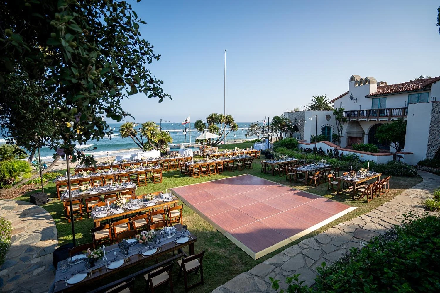 Wedding reception at Adamson House with long wooden banquet tables on the Back Lawn