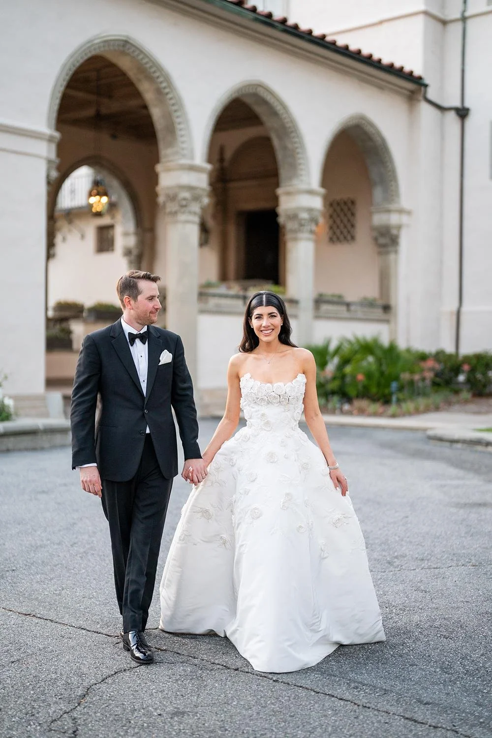 Wedding portraits of bride and groom walking together with the Athenaeum at Caltech behind them