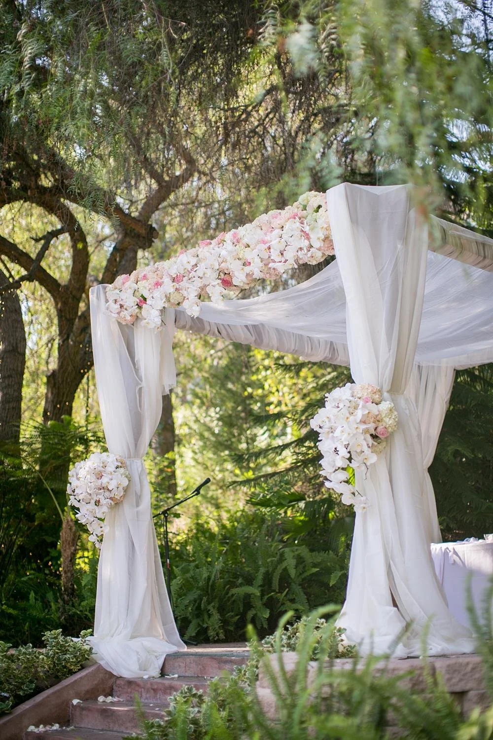 Wedding ceremony detail of chuppah decorated with pink roses and white orchids at The Vineyards Simi Valley