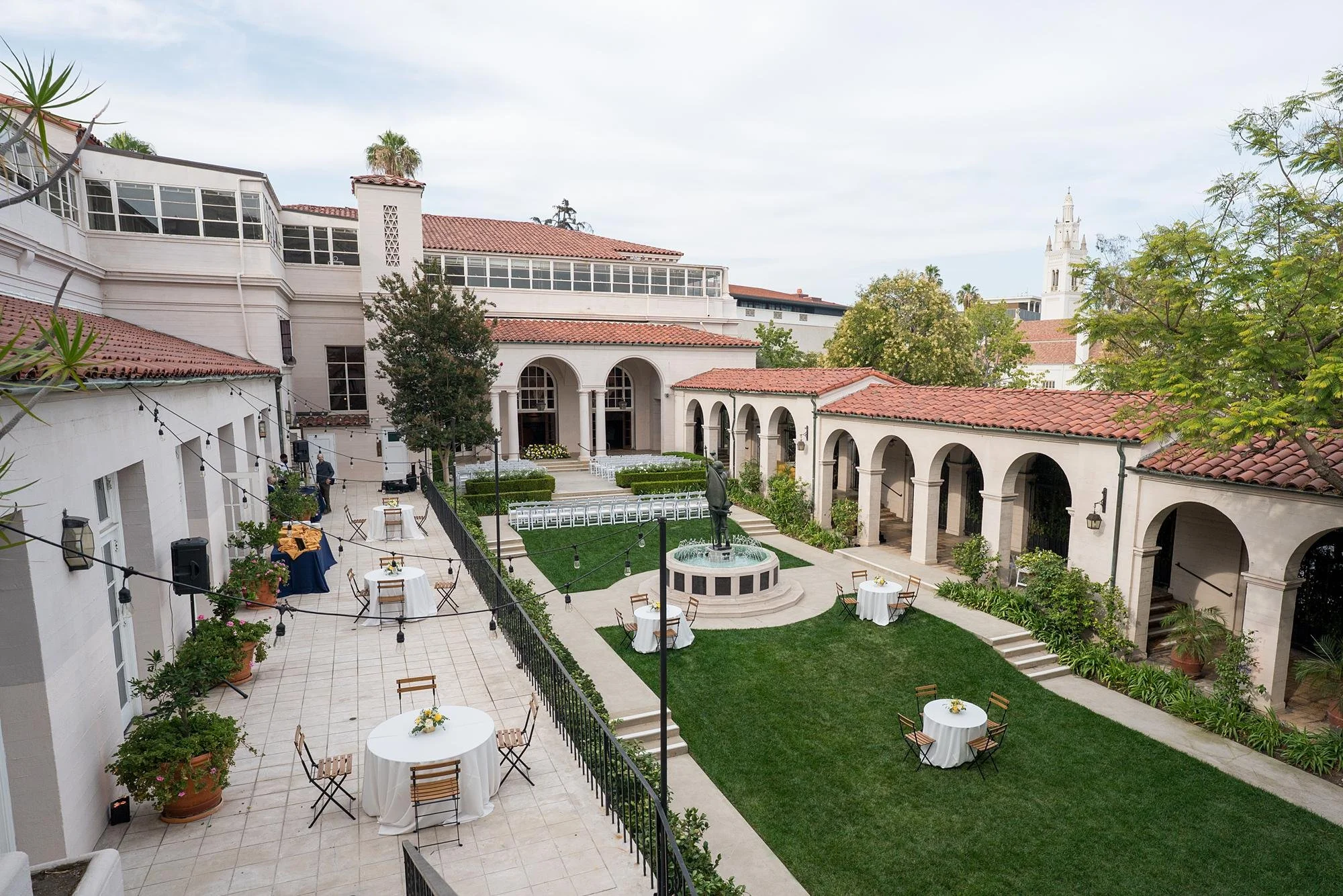 Garden wedding ceremony with view of historic building, tiled roof, and fountain at Ebell of Los Angeles