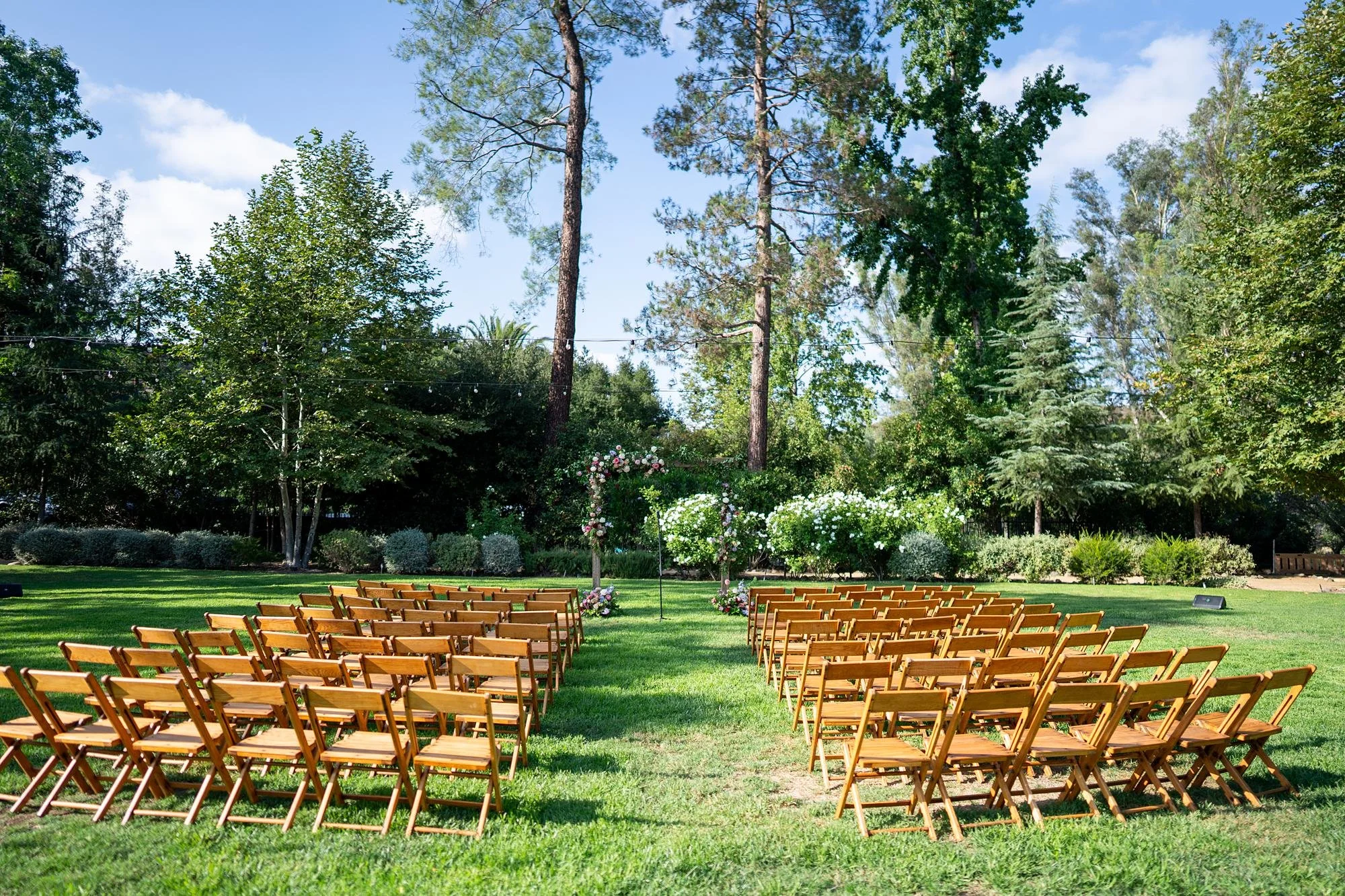 Wedding ceremony on the lawn at the Lodge at Malibou Lake with an arch decorated in colorful roses