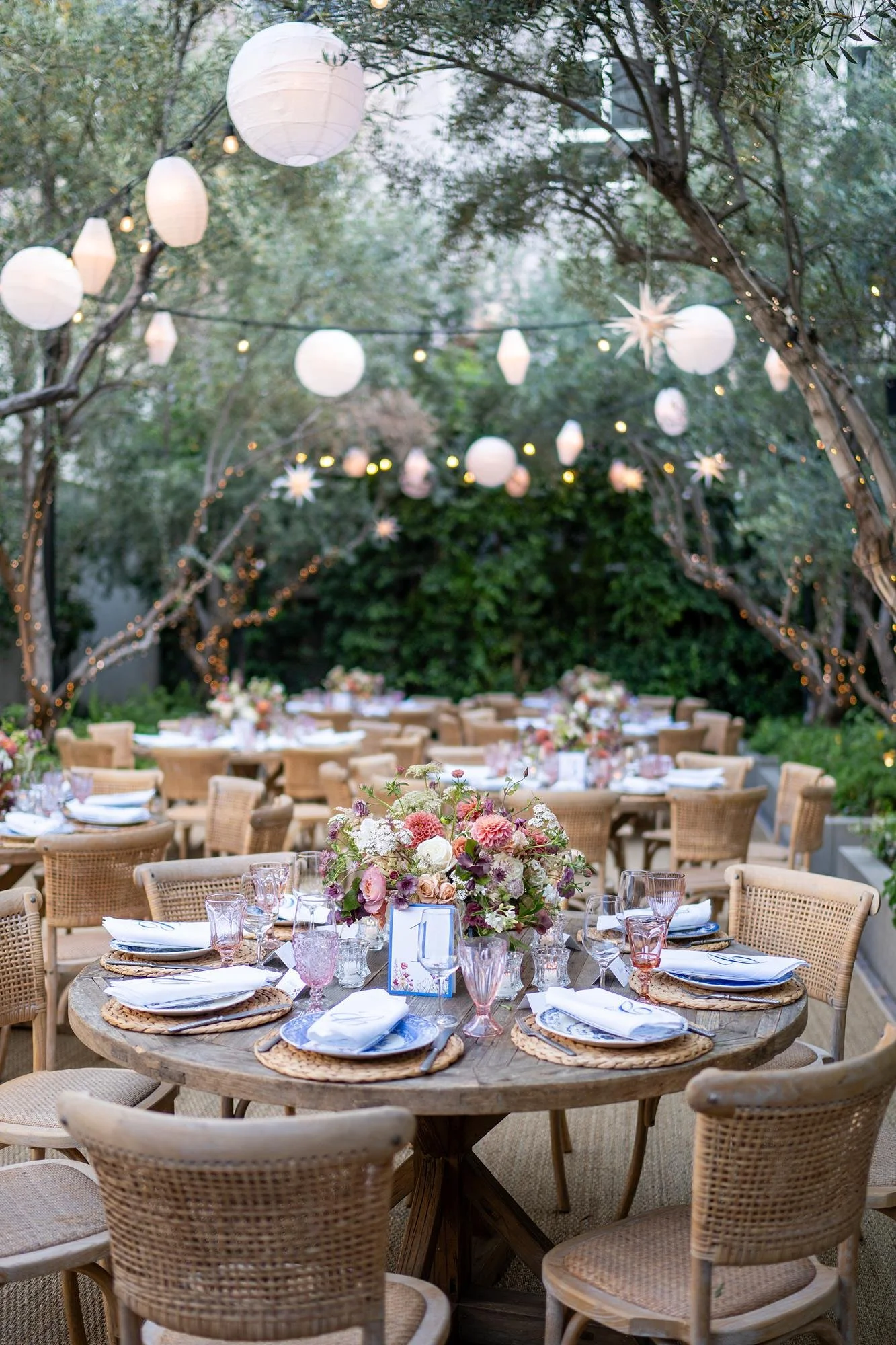 Dinner table centerpiece beneath lanterns during a wedding reception in Redbird Garden at Vibiana in Los Angeles