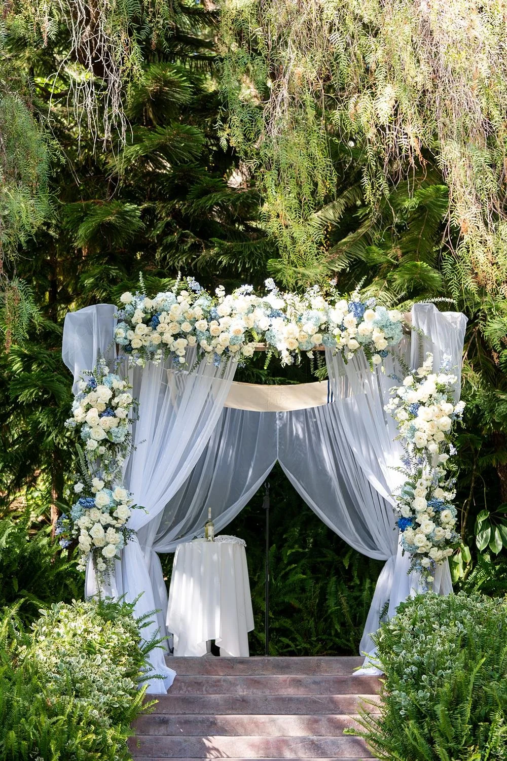 Wedding ceremony detail of chuppah decorated with white and blue florals at The Vineyards Simi Valley