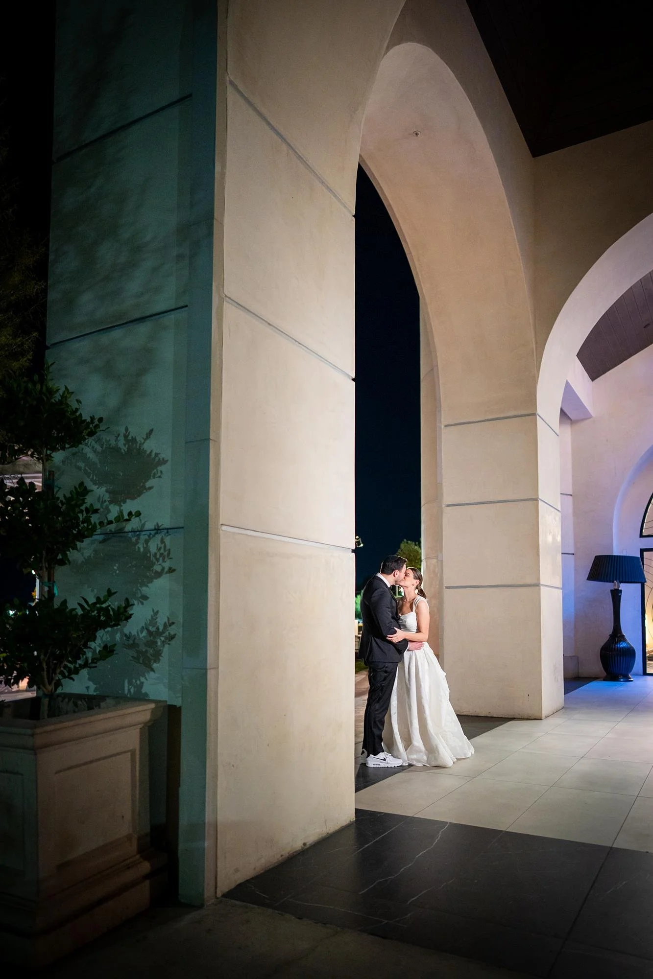 Wedding portraits at Landmark Mission Hills with couple kissing under arch at night