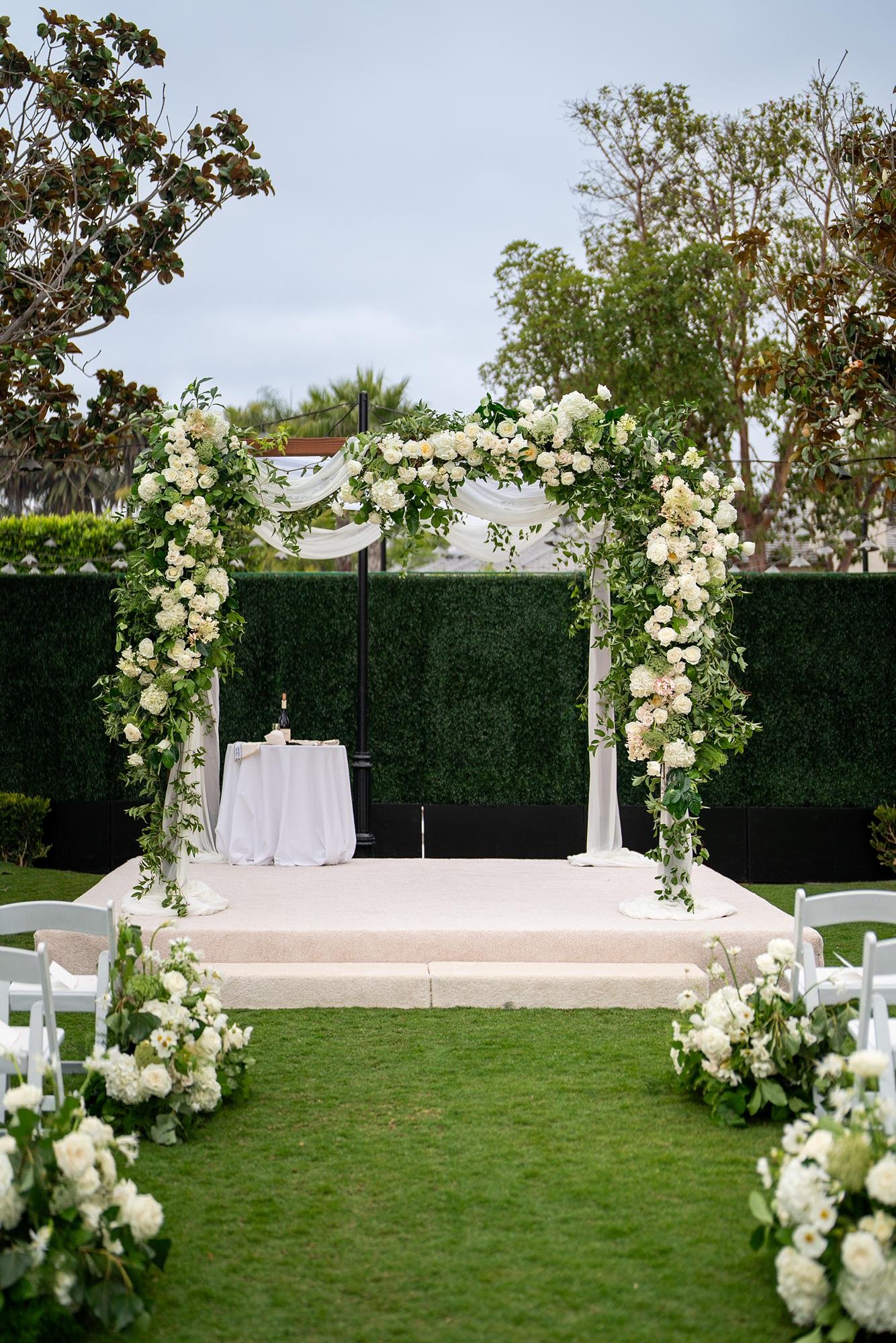 Close-up of a Jewish wedding chuppah draped in white florals and greenery at Rosewood Miramar Beach