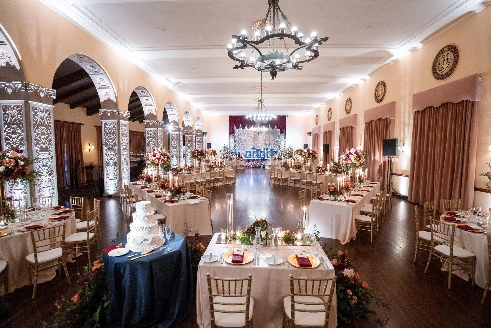 Dining Room wedding reception with red and pink florals, lit arches and swing band at Ebell of Los Angeles
