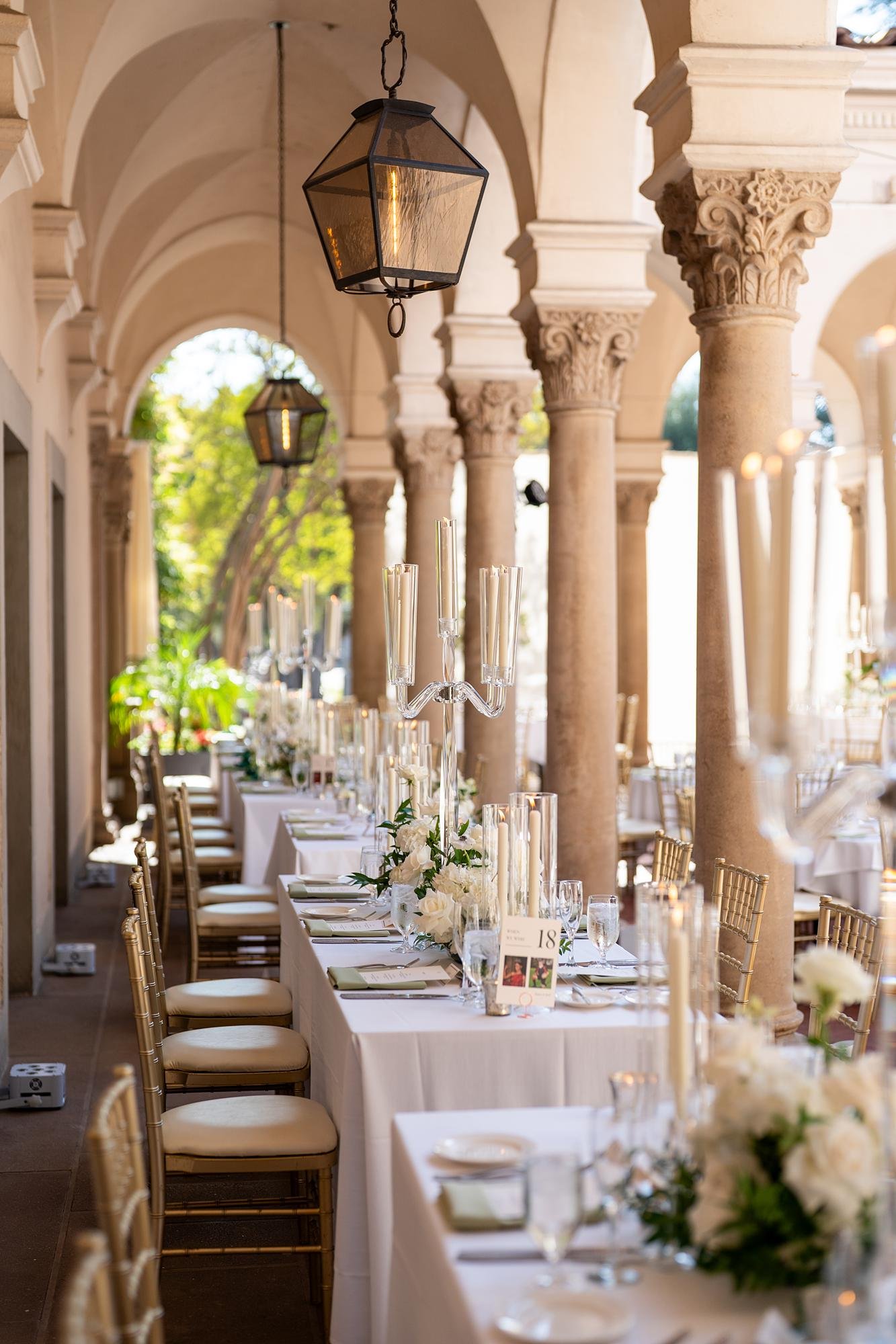 Inner Courtyard wedding reception tables with white florals and candles beneath arches at the Athenaeum at Caltech