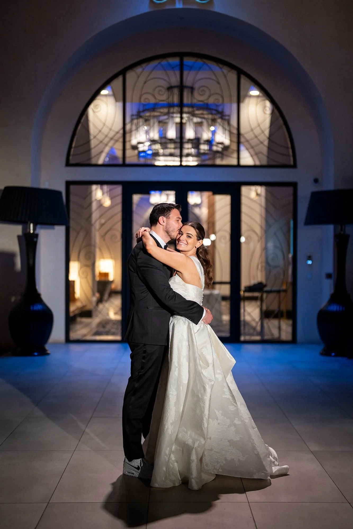 Wedding portraits at Landmark Mission Hills with couple hugging at illuminated entrance at night