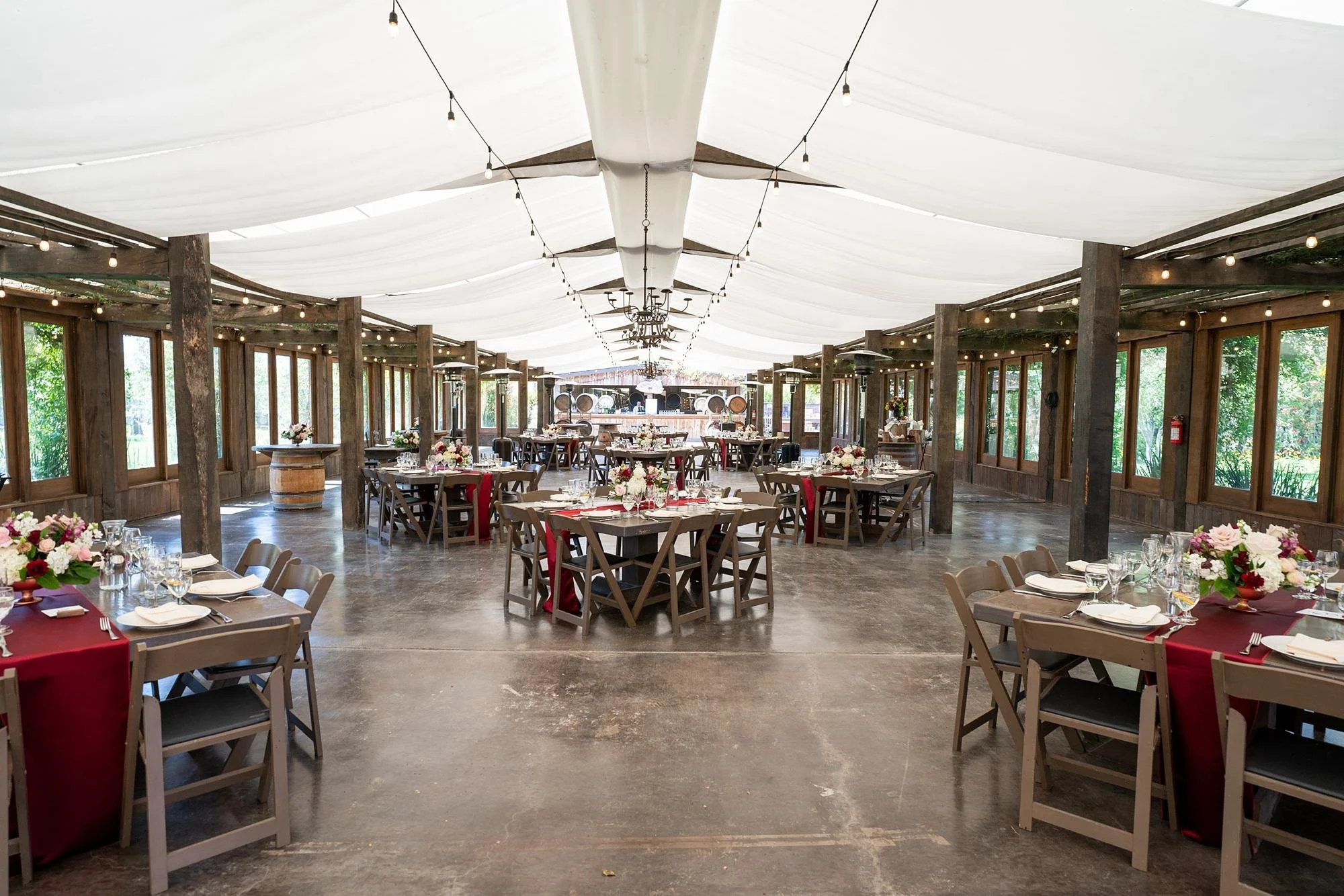 Wedding reception tables in the Pavilion at La Arboleda with red runners and red and pink centerpieces