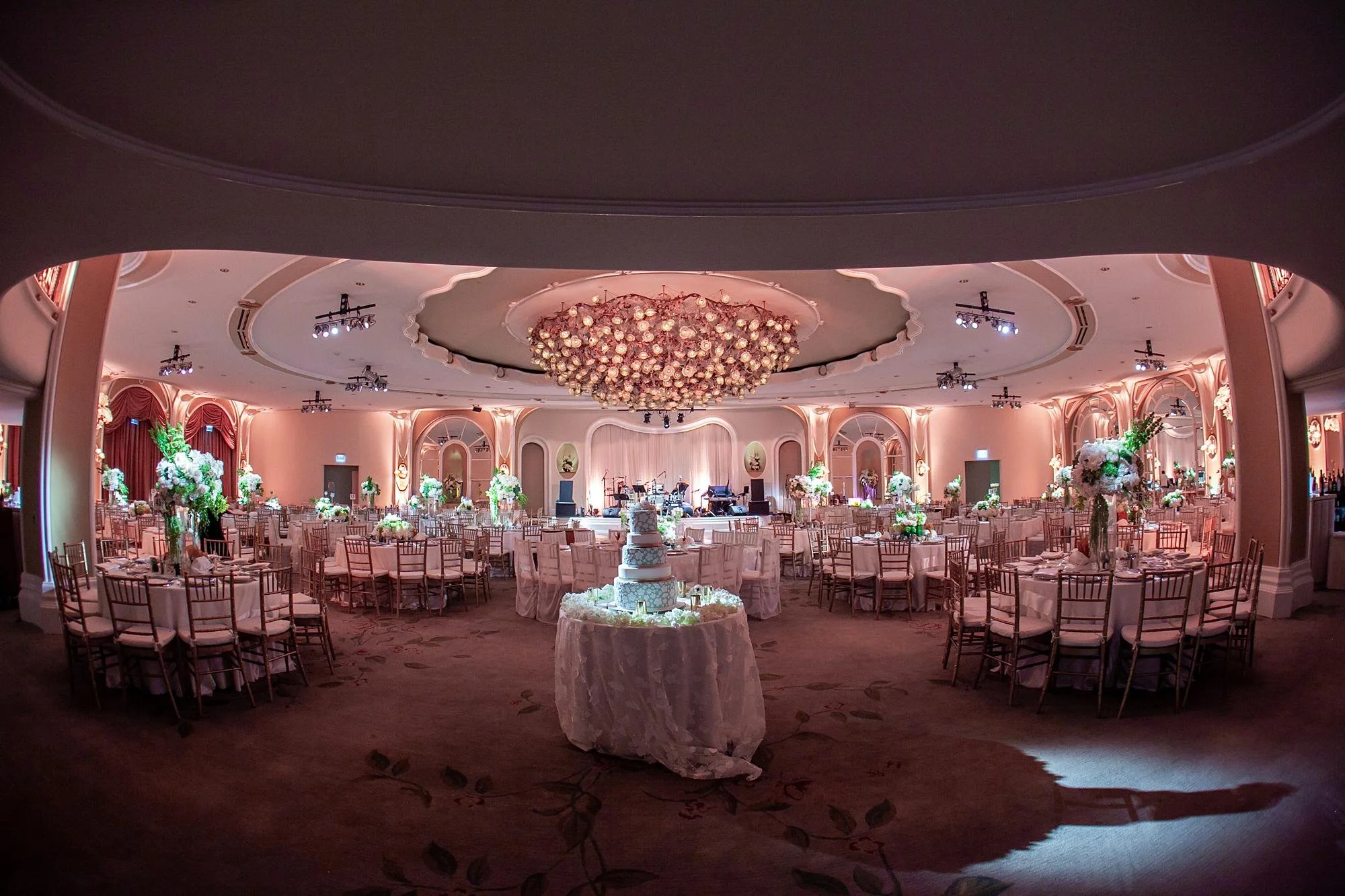 Wedding reception in the Crystal Ballroom at the Beverly Hills Hotel with florals, lighting, and white dance floor