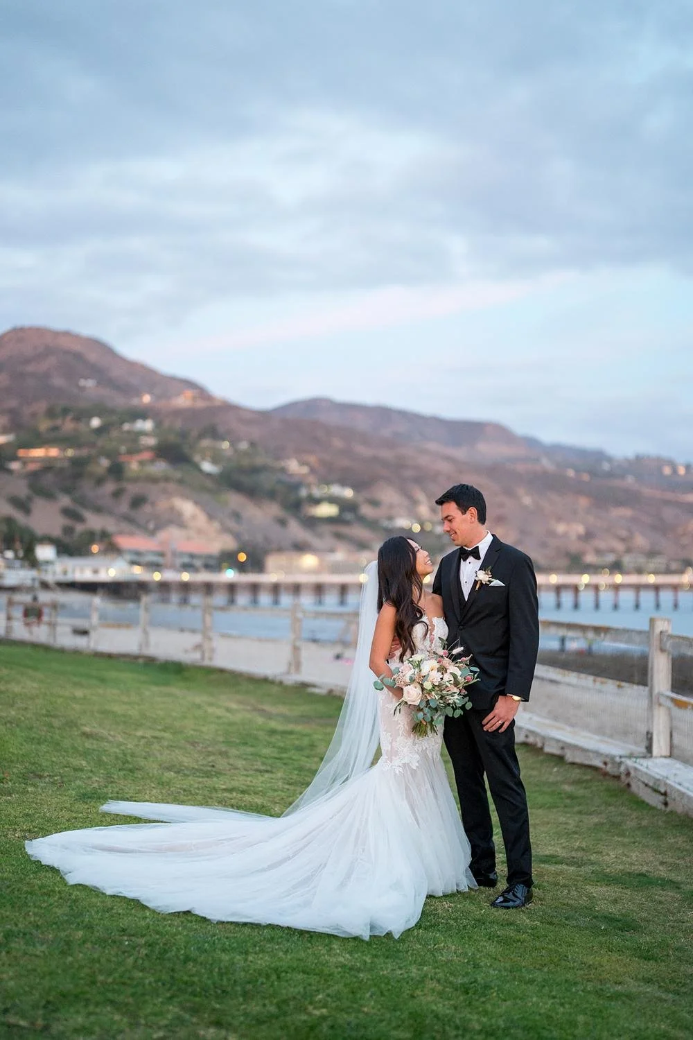 Wedding portraits at Adamson House with the Malibu coastline and pier behind the couple
