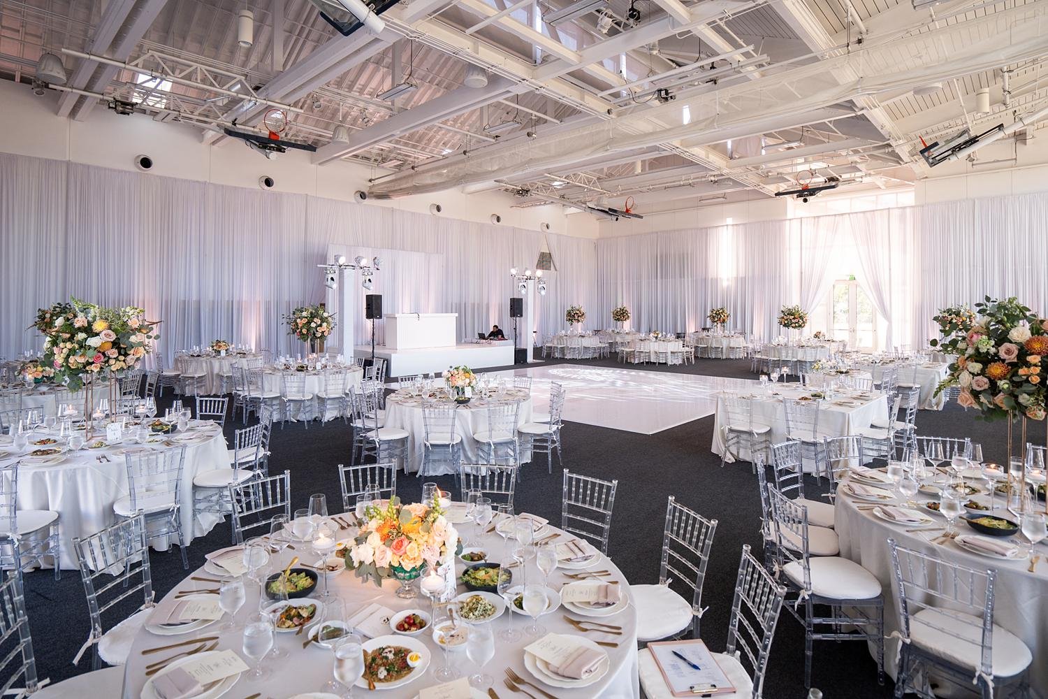 Wedding reception wide view of decorated ballroom with florals, drapery, and lighting at Stephen Wise Temple