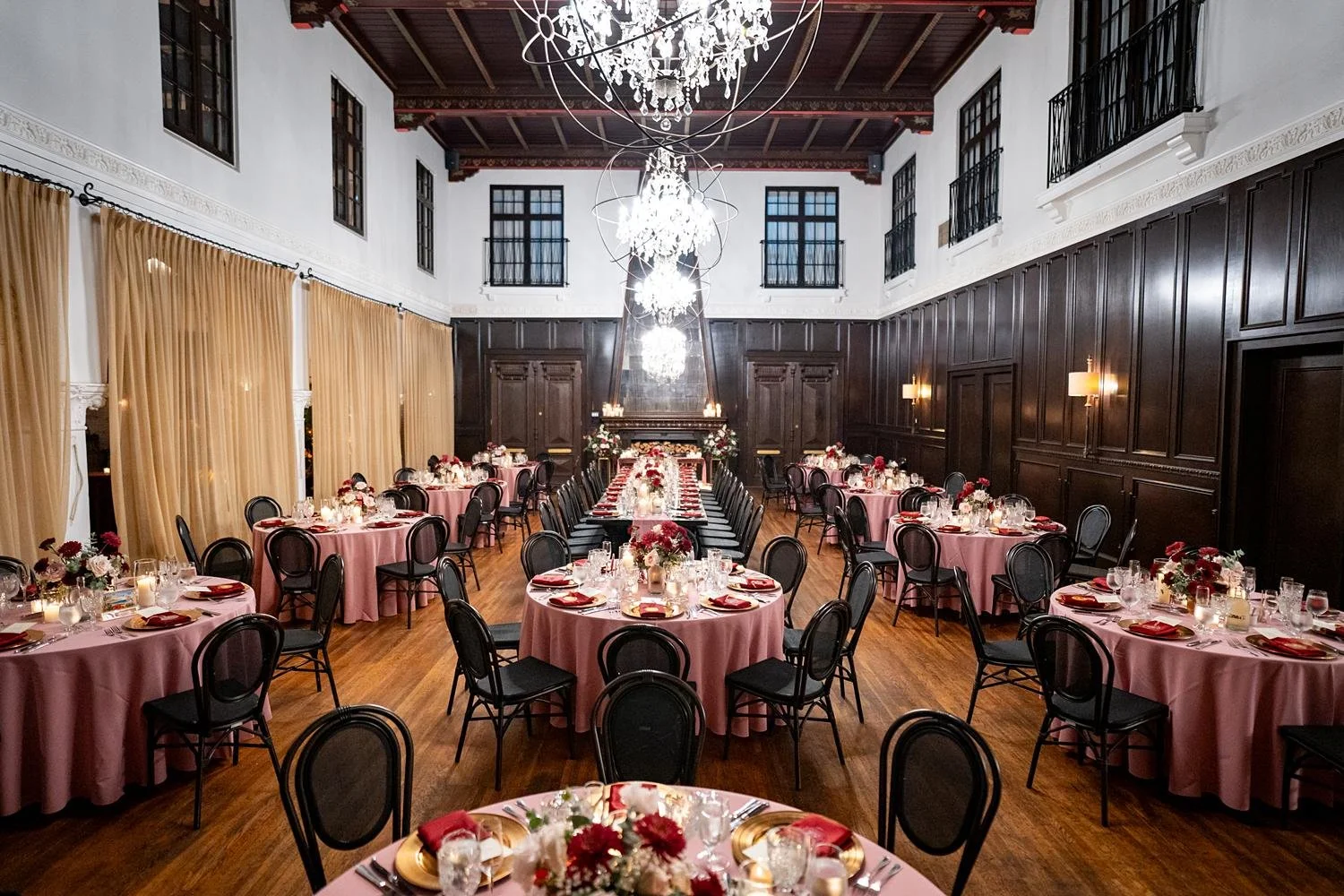 Wedding reception with round tables, pink linens and red florals at the Ebell of Long Beach