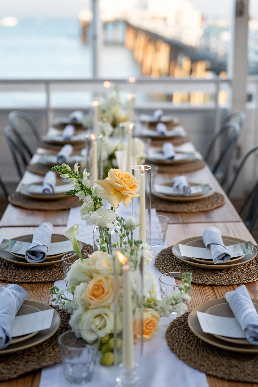 Wedding reception at Malibu Farm at the Pier with table decorated with candles and roses
