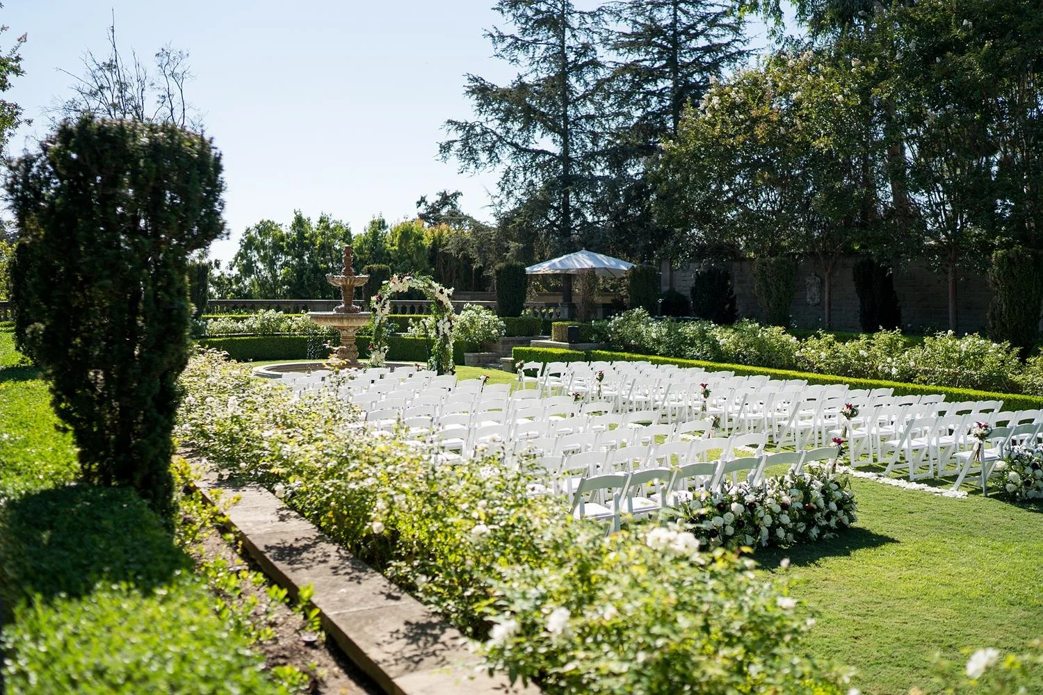 Wedding ceremony setup in the Formal Garden at Greystone Mansion with floral arch and guest seating