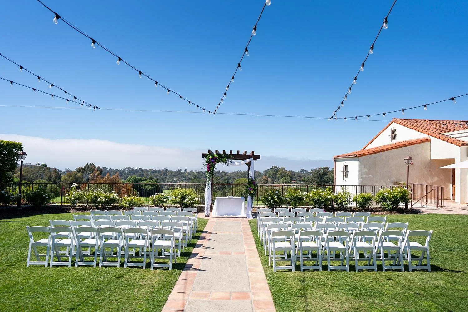 Wedding ceremony arch draped in white fabric with orchids and hydrangeas at Palos Verdes Golf Club