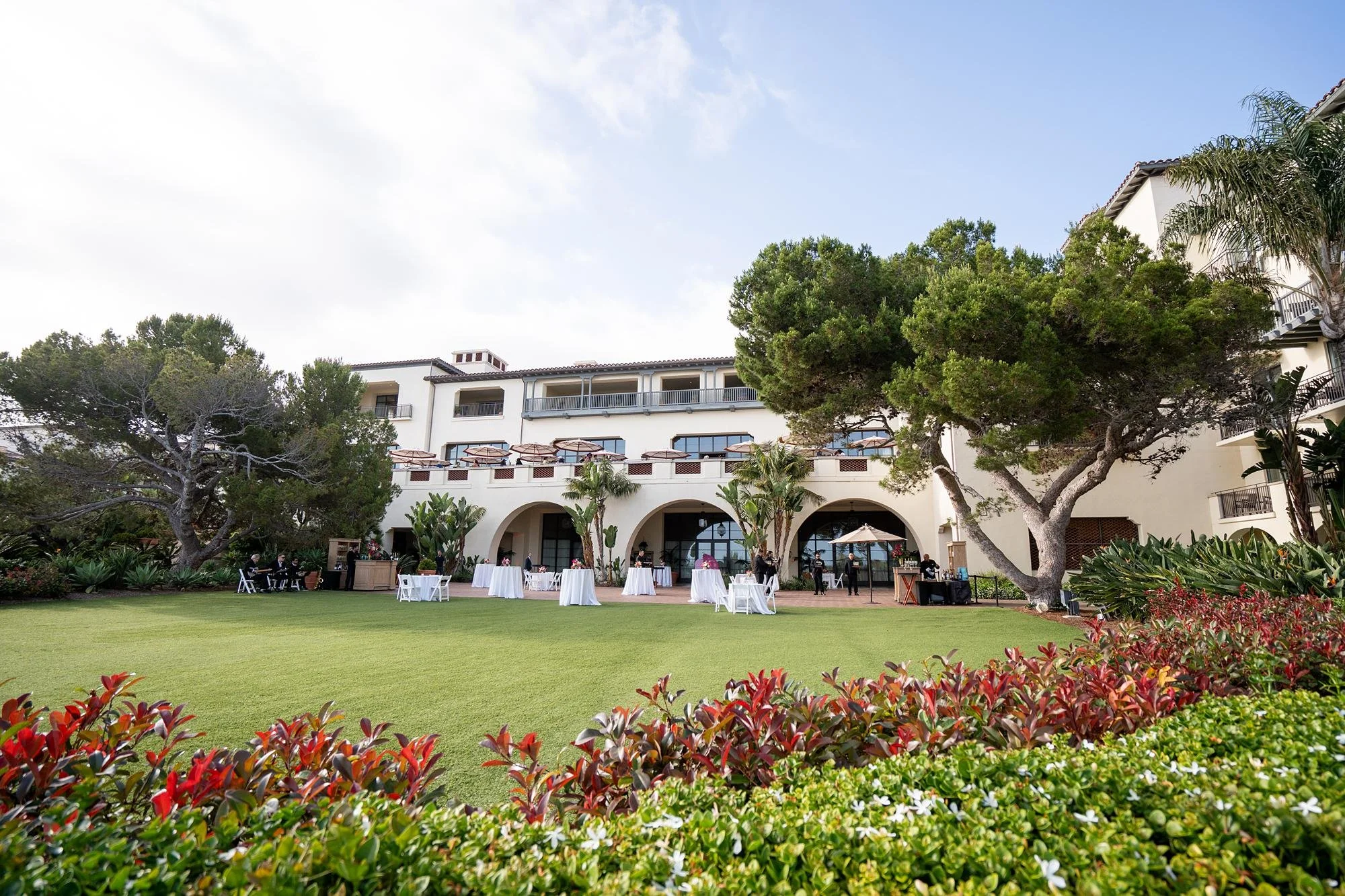 Cocktail tables set on Catalina Lawn with resort building in background during wedding celebration at Terranea Resort
