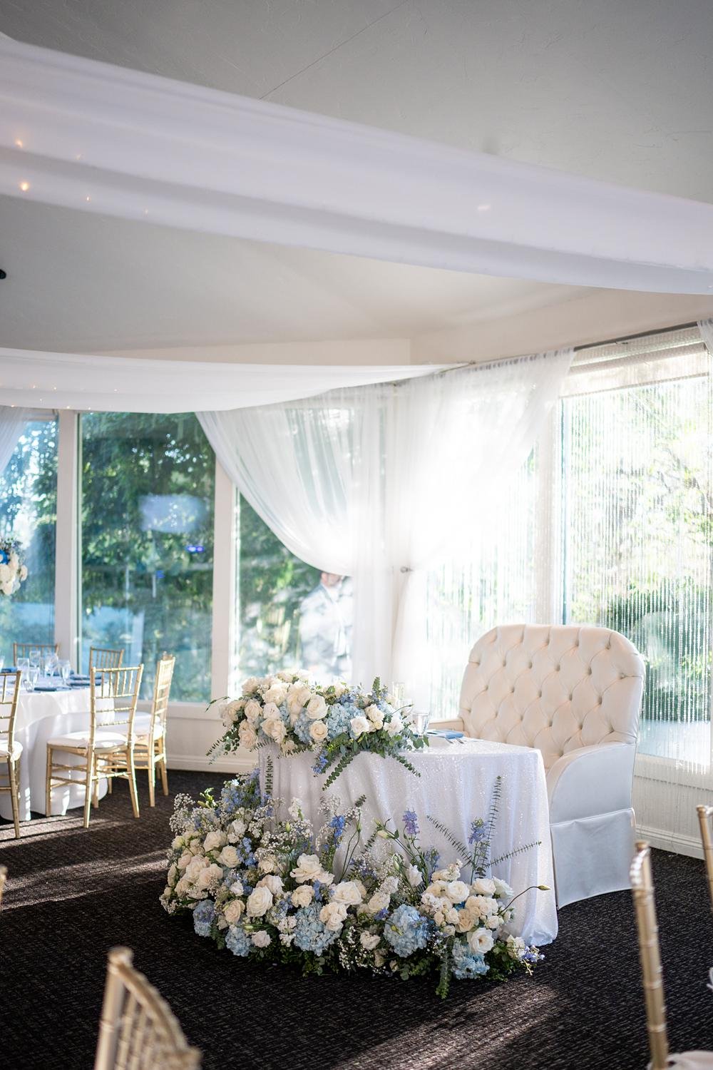 Wedding reception detail of sweetheart table decorated with blue and white florals at The Vineyards Simi Valley