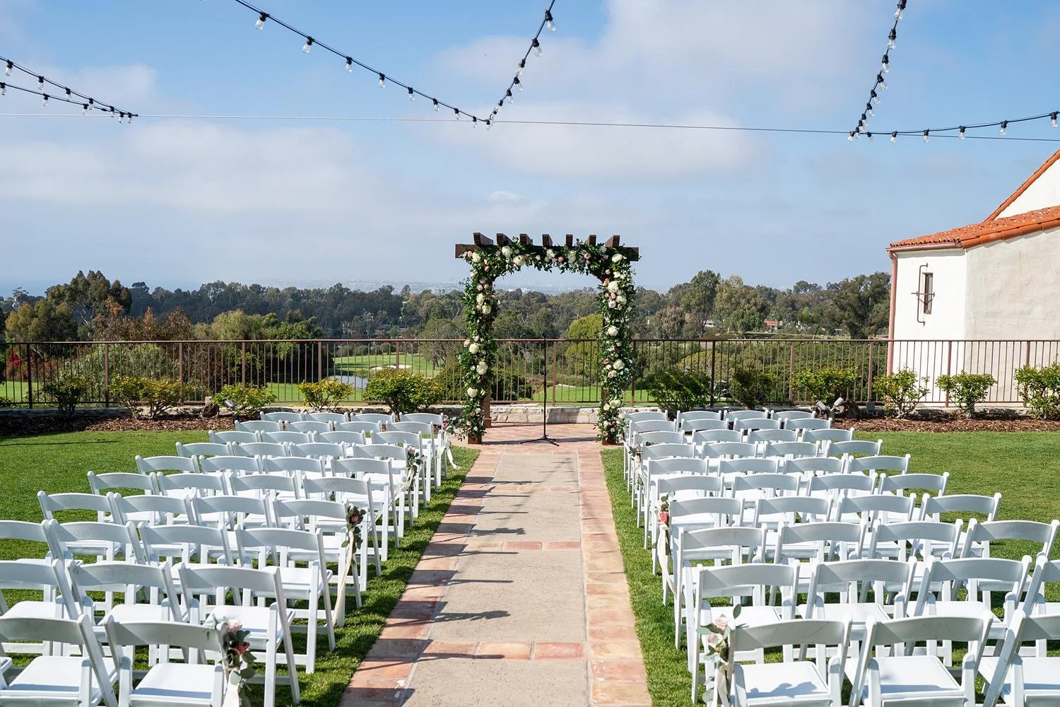 Wedding ceremony with white and purple floral arch at Palos Verdes Golf Club