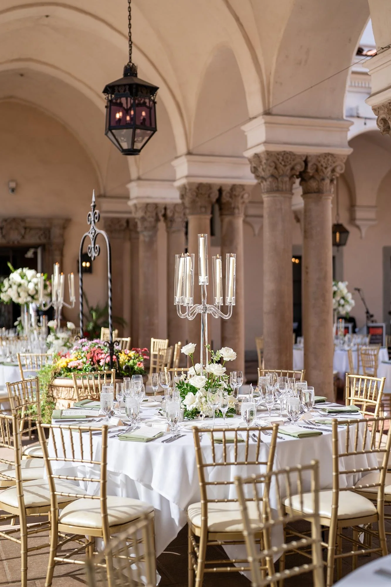 Inner Courtyard wedding reception long table with white florals and glass candelabras under arches at the Athenaeum at Caltech