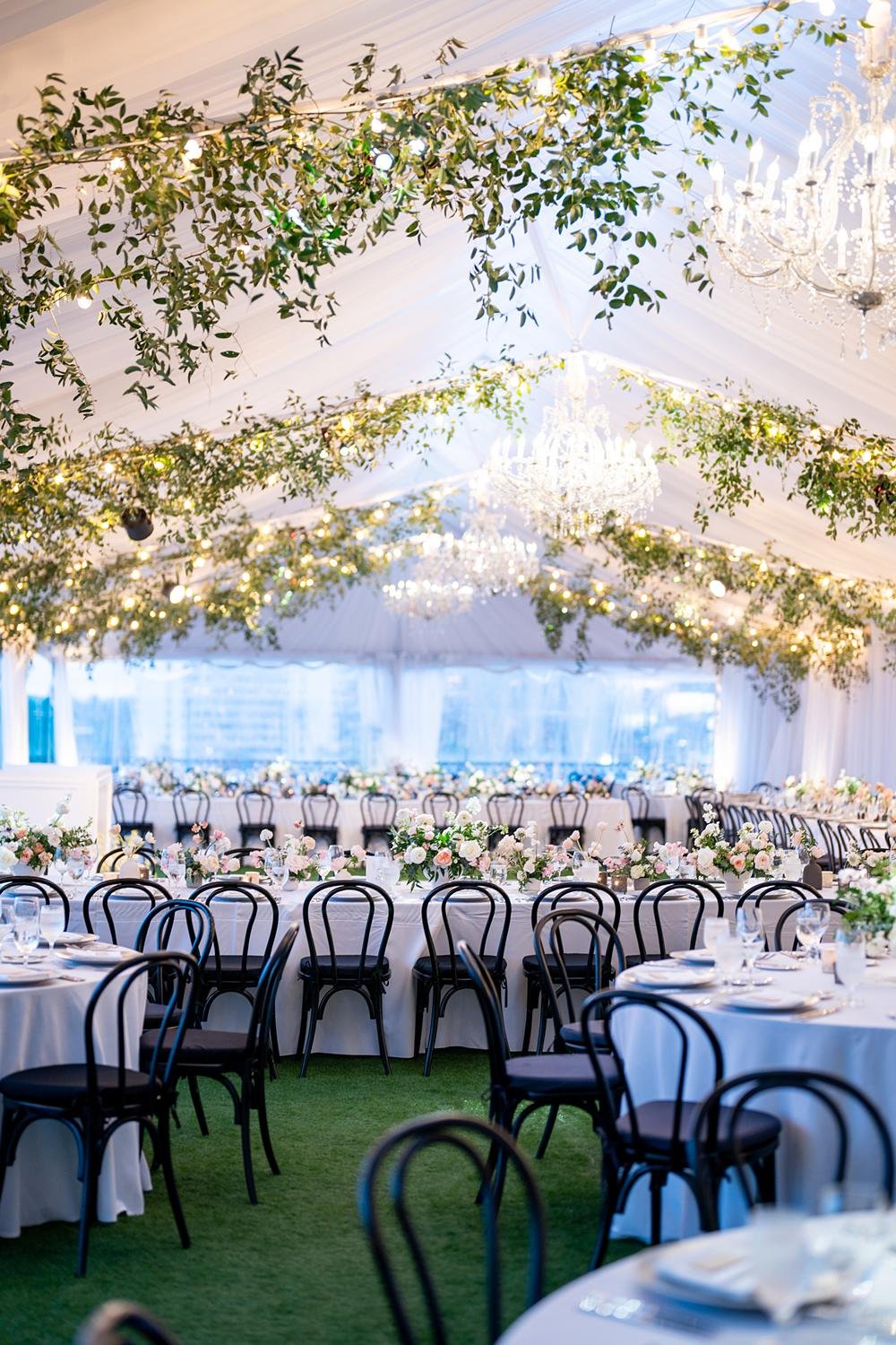 Wedding reception on the West End Rooftop at the London West Hollywood with tables beneath chandeliers and garland-draped ceiling