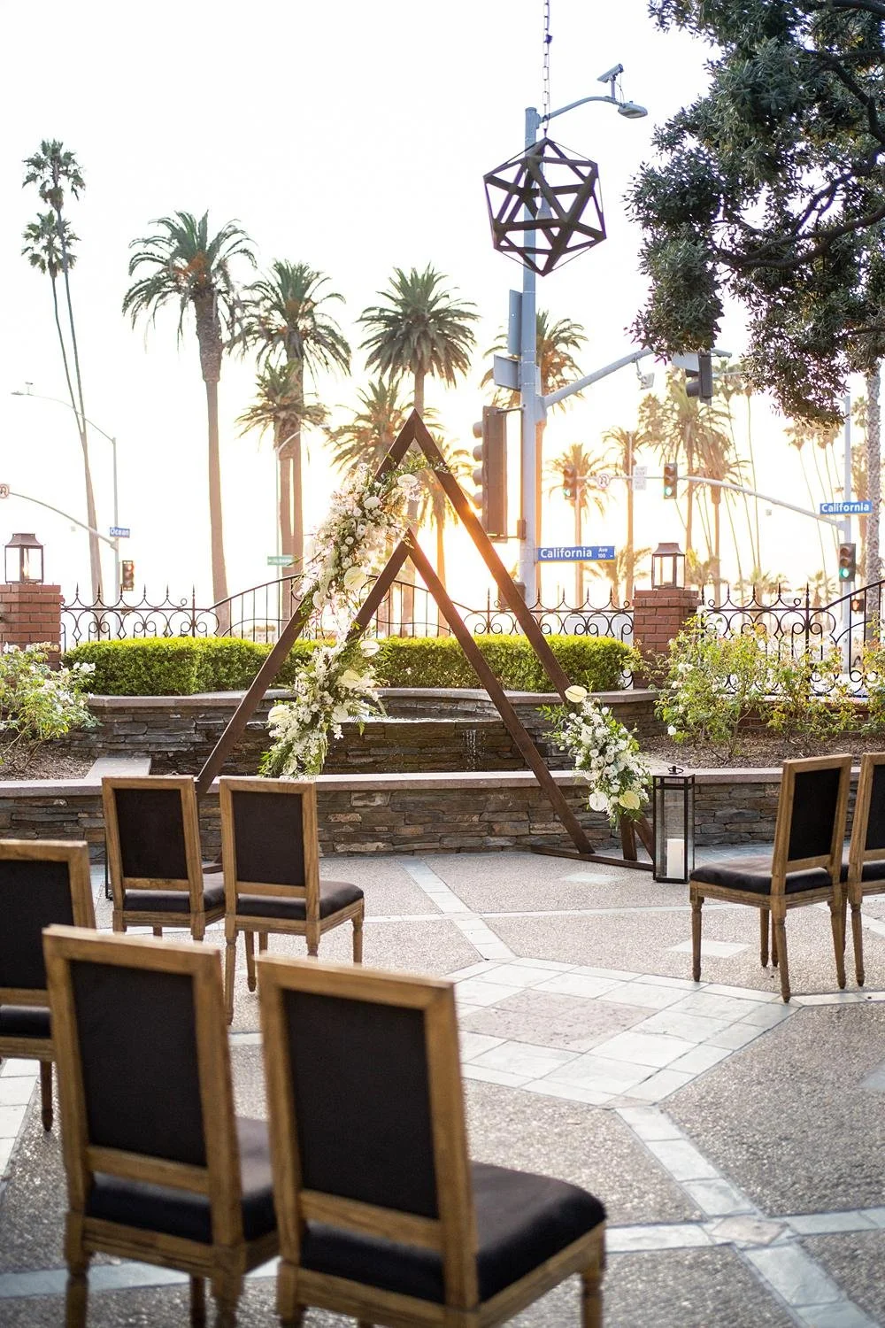 Golden hour image of Sunset Terrace wedding ceremony with modern triangle arch at Fairmont Miramar