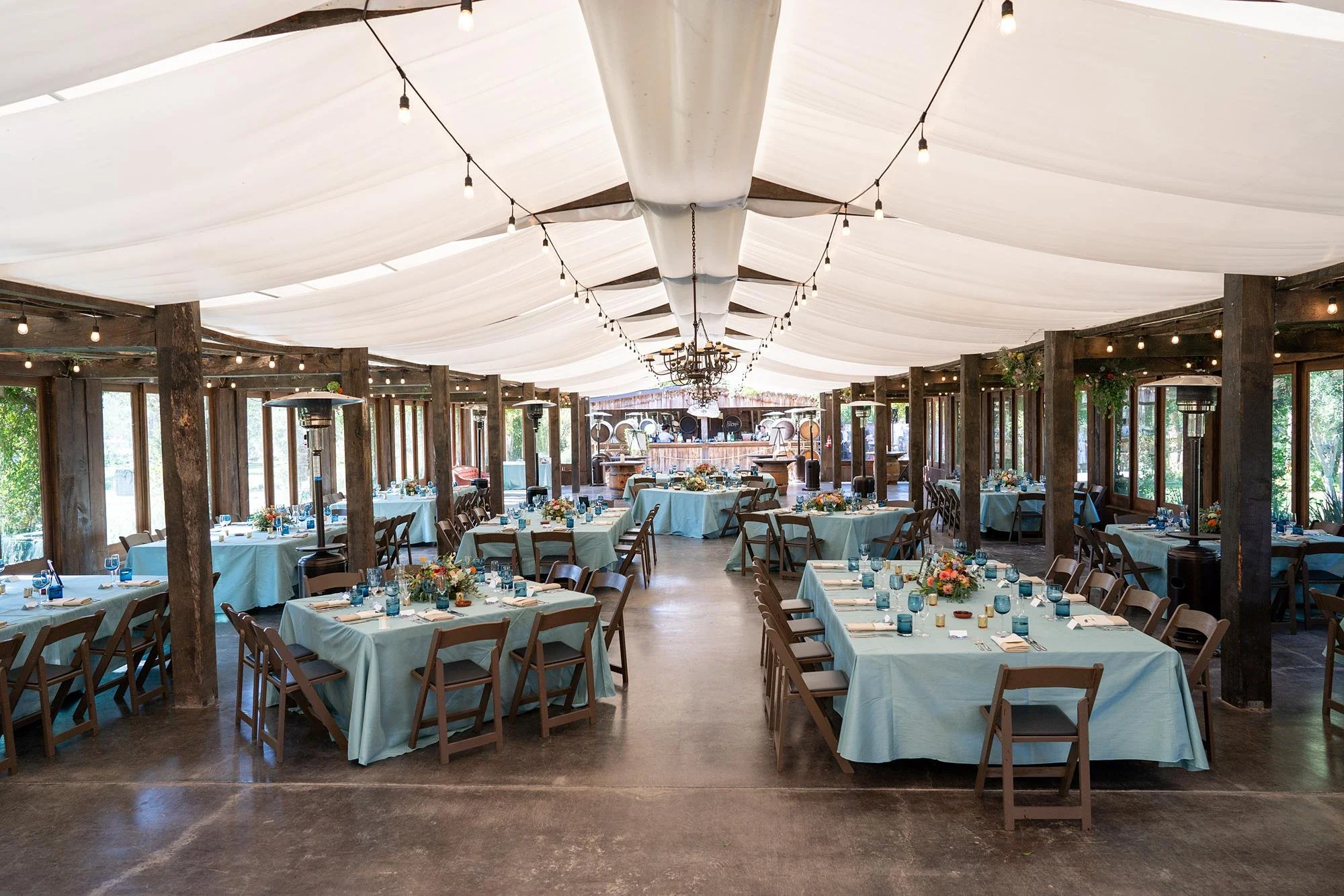 Wedding reception décor in the Pavilion at La Arboleda featuring blue-themed table settings