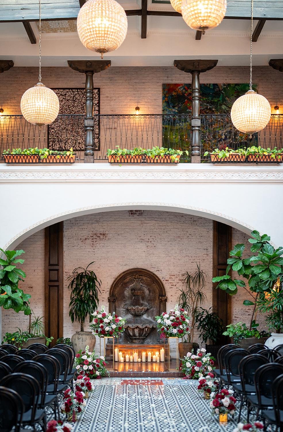 Wedding ceremony arch with roses and candles in front of fountain at the Ebell of Long Beach