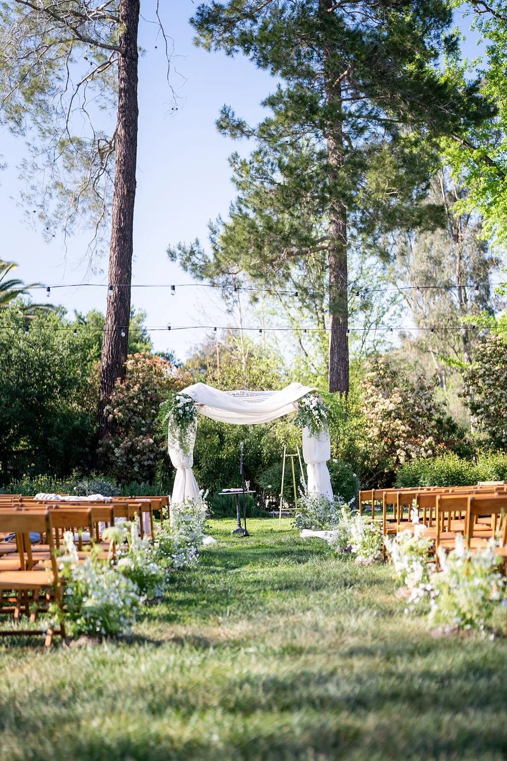 Wedding ceremony on the lawn at the Lodge at Malibou Lake with a white draped arch