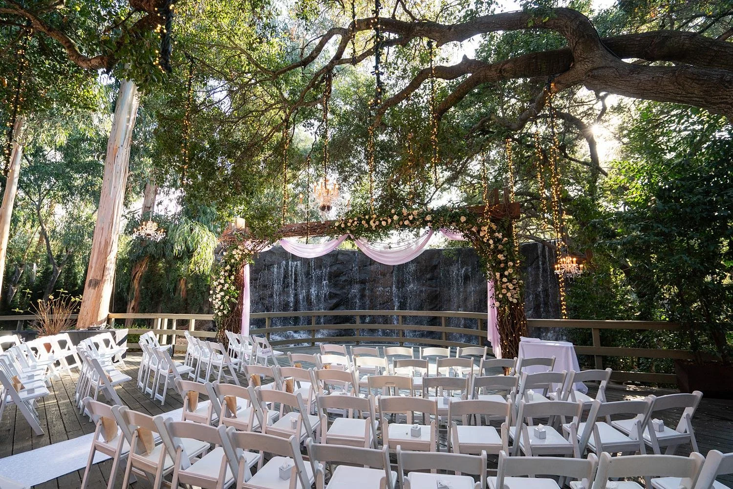 Wedding ceremony at Calamigos Ranch with a white fabric arch decorated in cascading roses