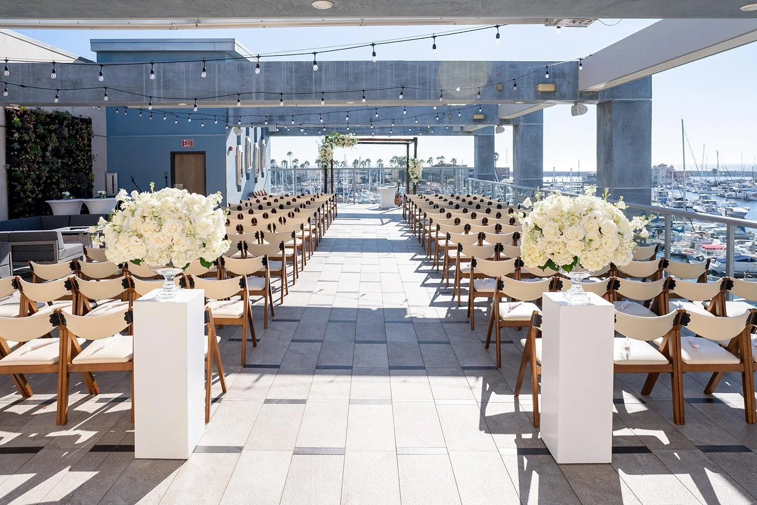 Wedding ceremony at Shade Hotel Redondo Beach on the Sky Level with rose arrangements on pedestals lining aisle