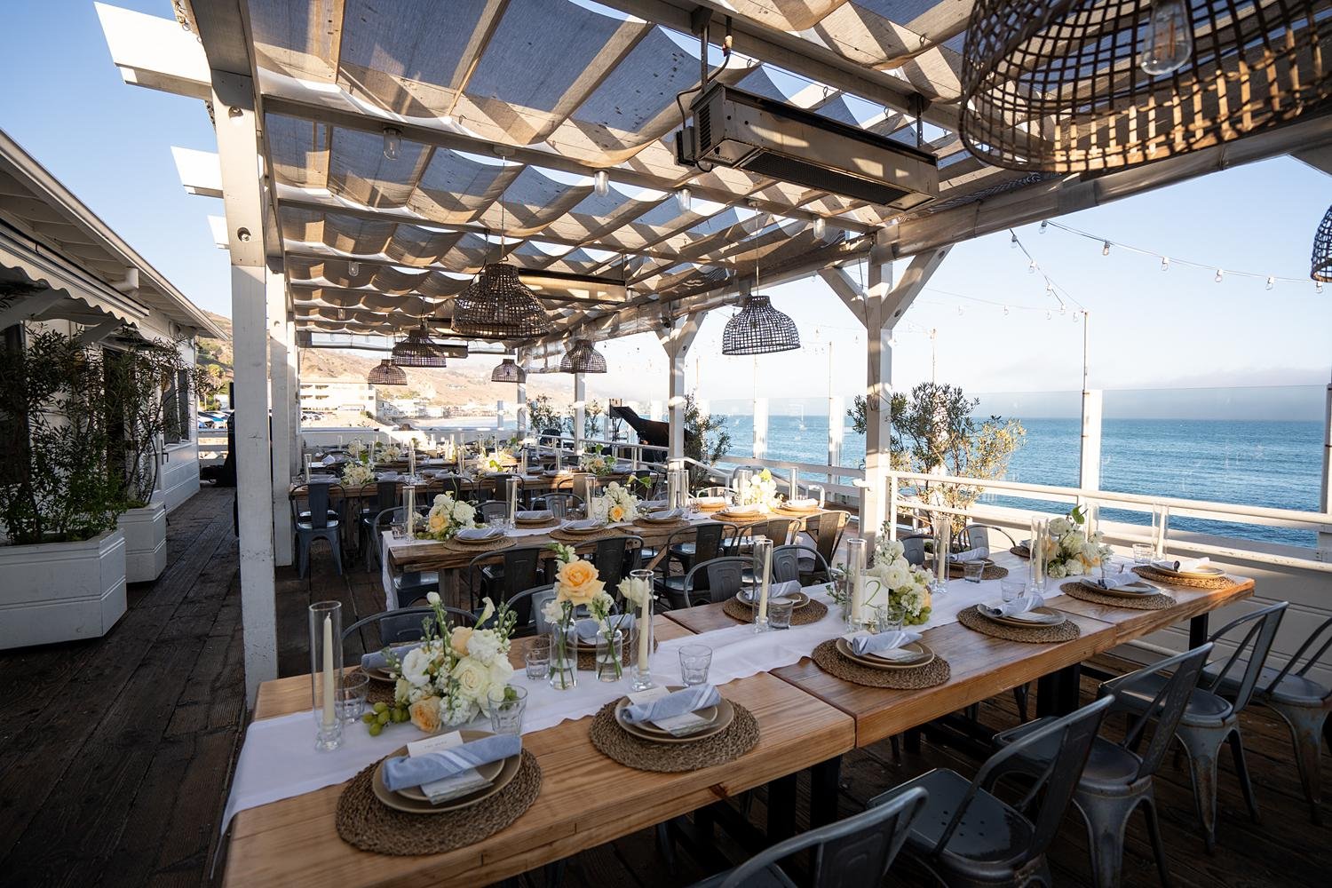 Wedding reception at Malibu Farm at the Pier with tables set and ocean in background