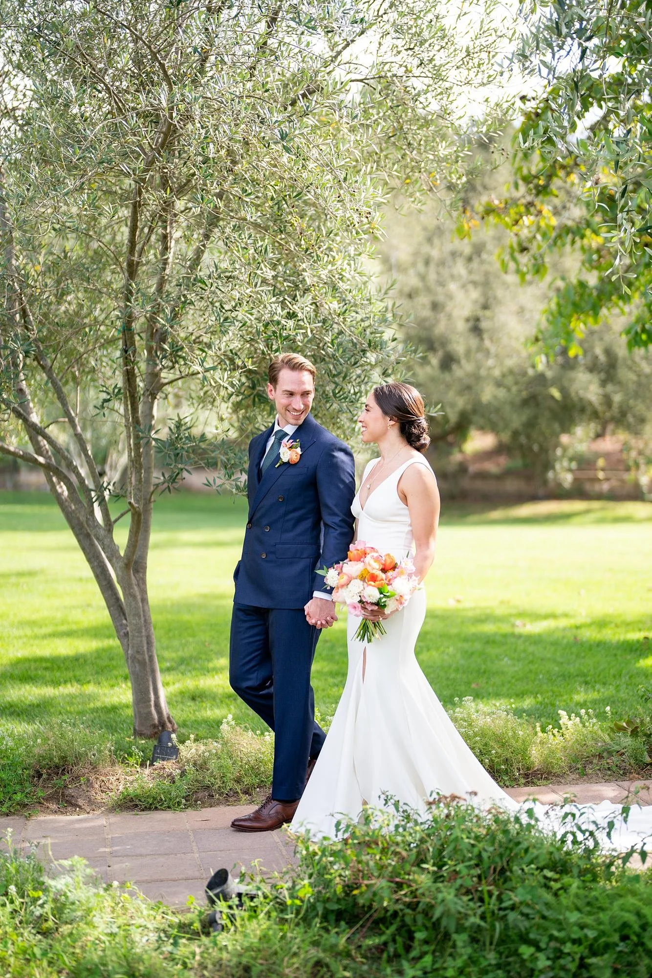 Wedding portrait of bride and groom walking along a tree-lined path at La Arboleda