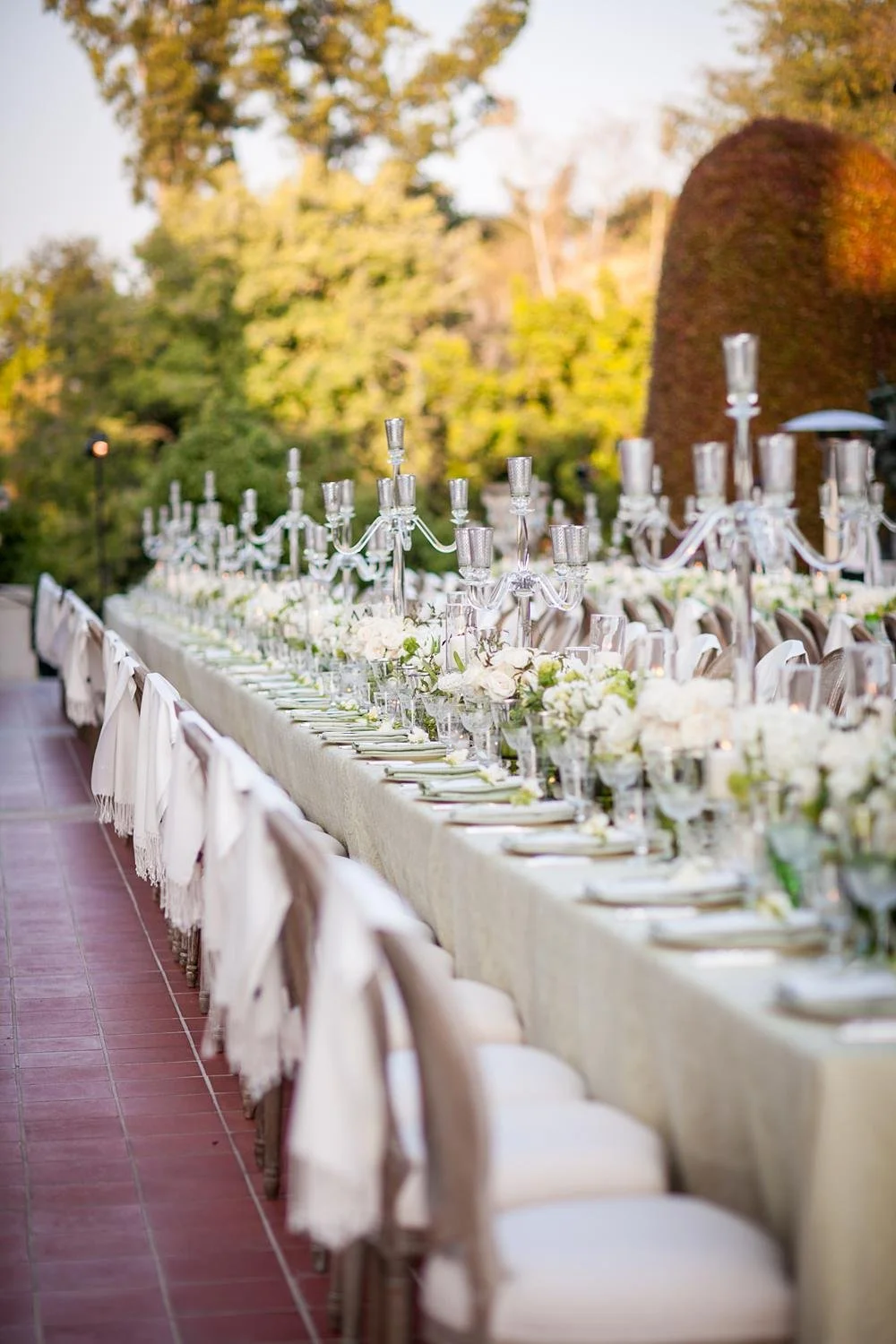 Long reception tables at the South Terrace with florals, candles and pashminas draped over chairs at Huntington Library