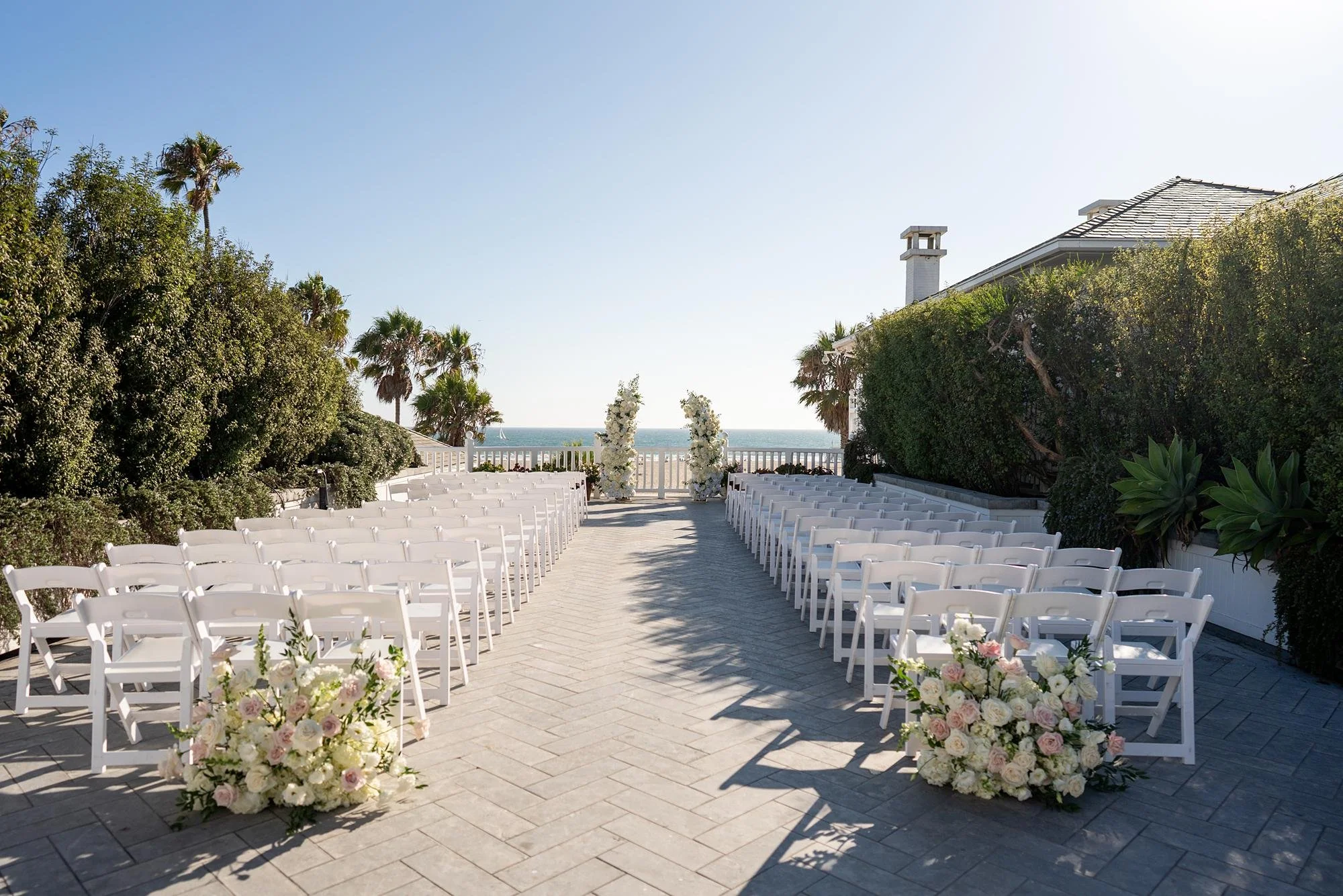 Wedding ceremony on Pacific Terrace at Shutters on the Beach with a modern floral arch in white and pink