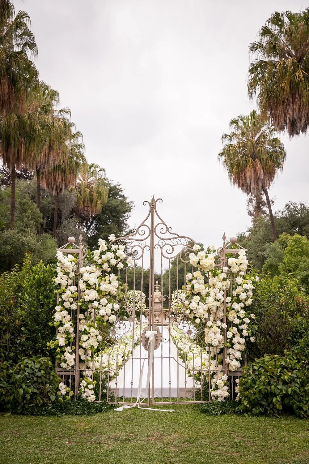 Wedding ceremony featuring iron gate with cascading roses leading to North Visa Lawn at Huntington Library