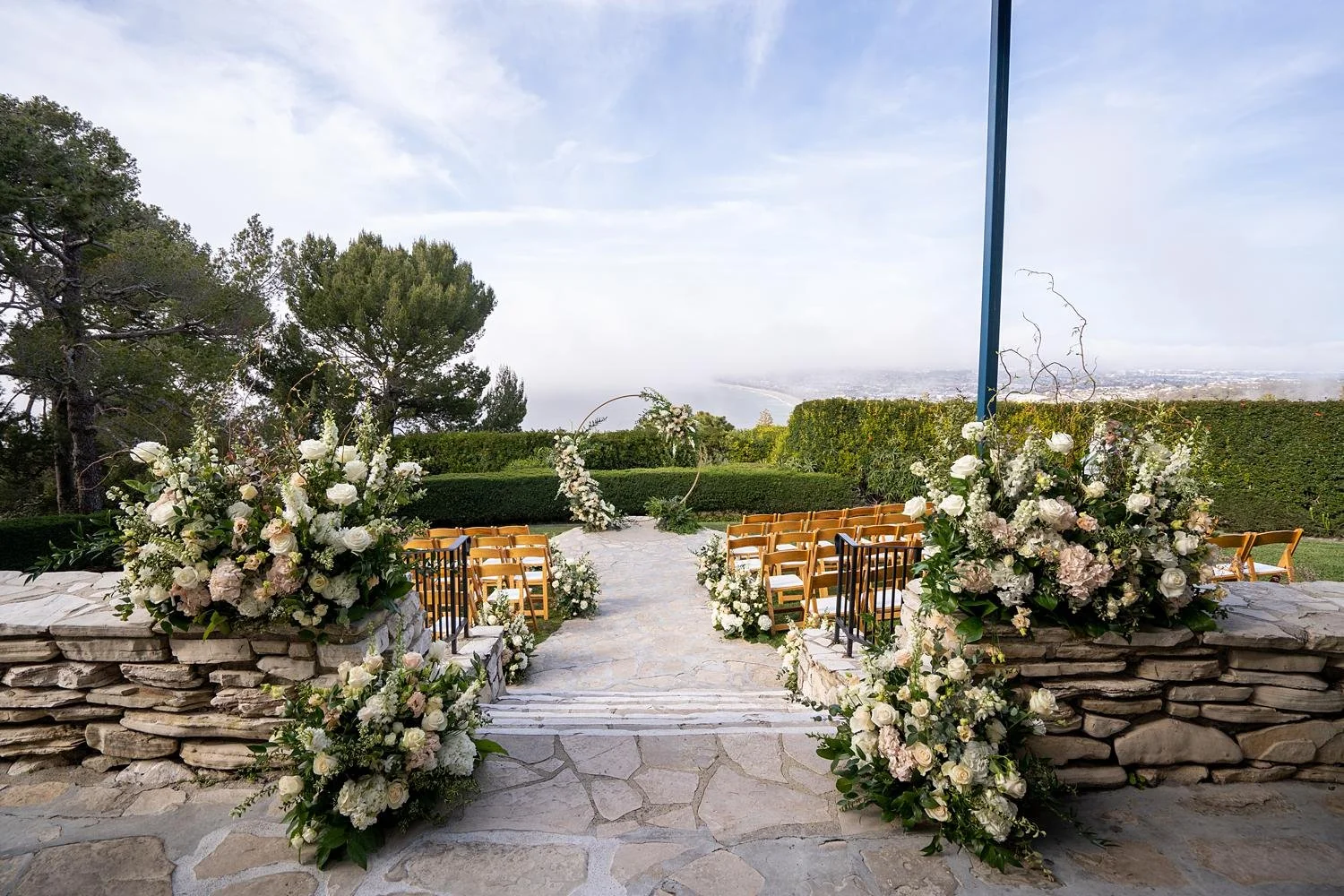 Wedding ceremony on the lawn with white and peach florals and circular arch at La Venta Inn