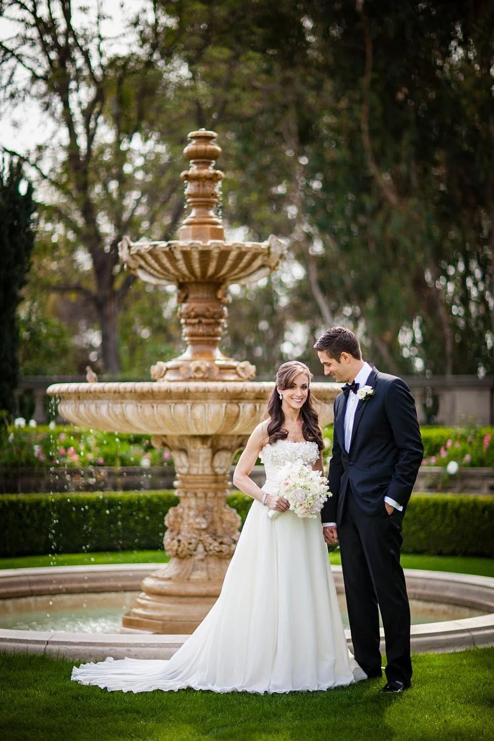 Wedding portrait of bride and groom standing at the fountain in the Formal Garden at Greystone Mansion