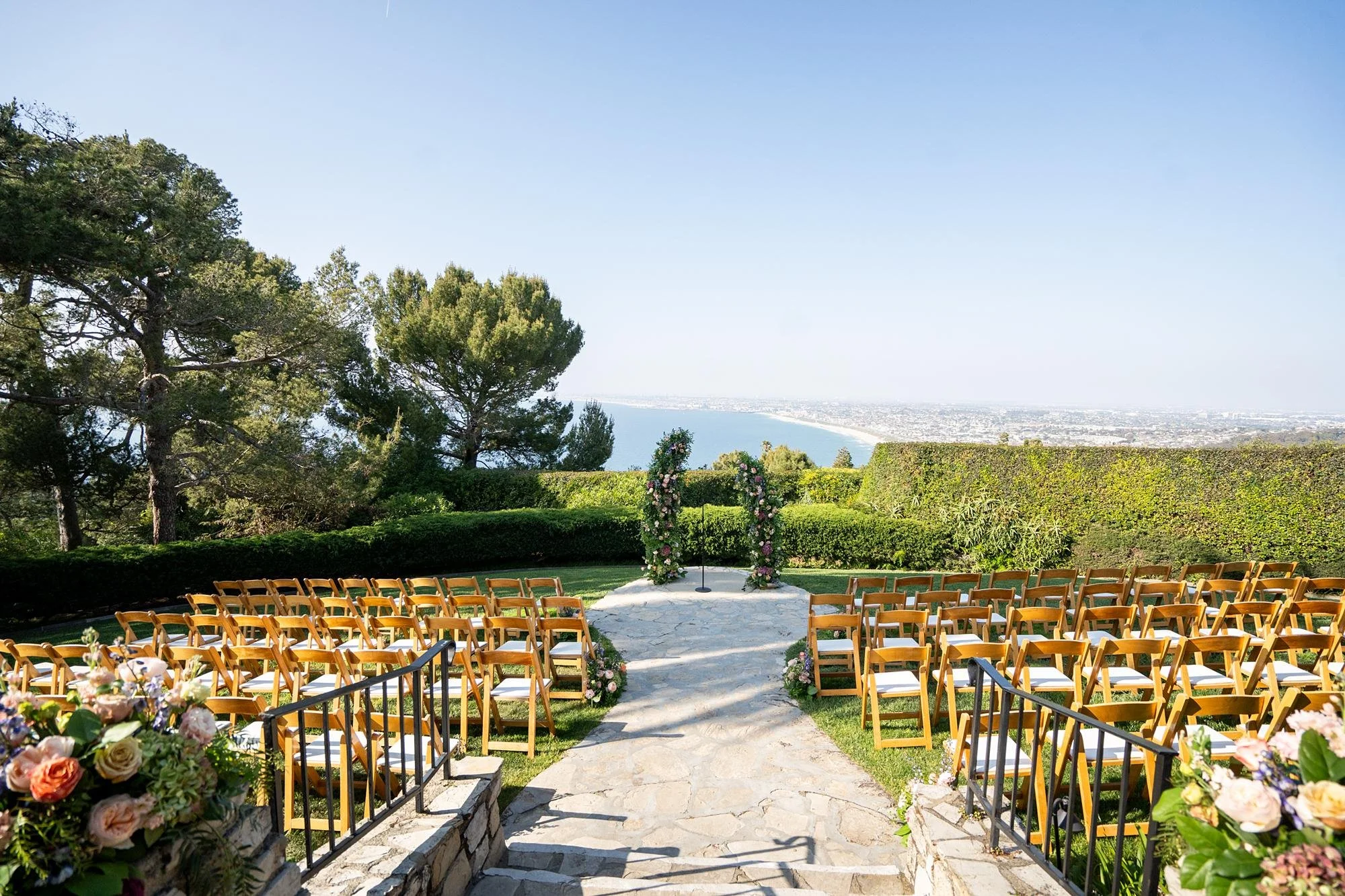 Wedding ceremony with modern garden rose arch with California coastline view at La Venta Inn