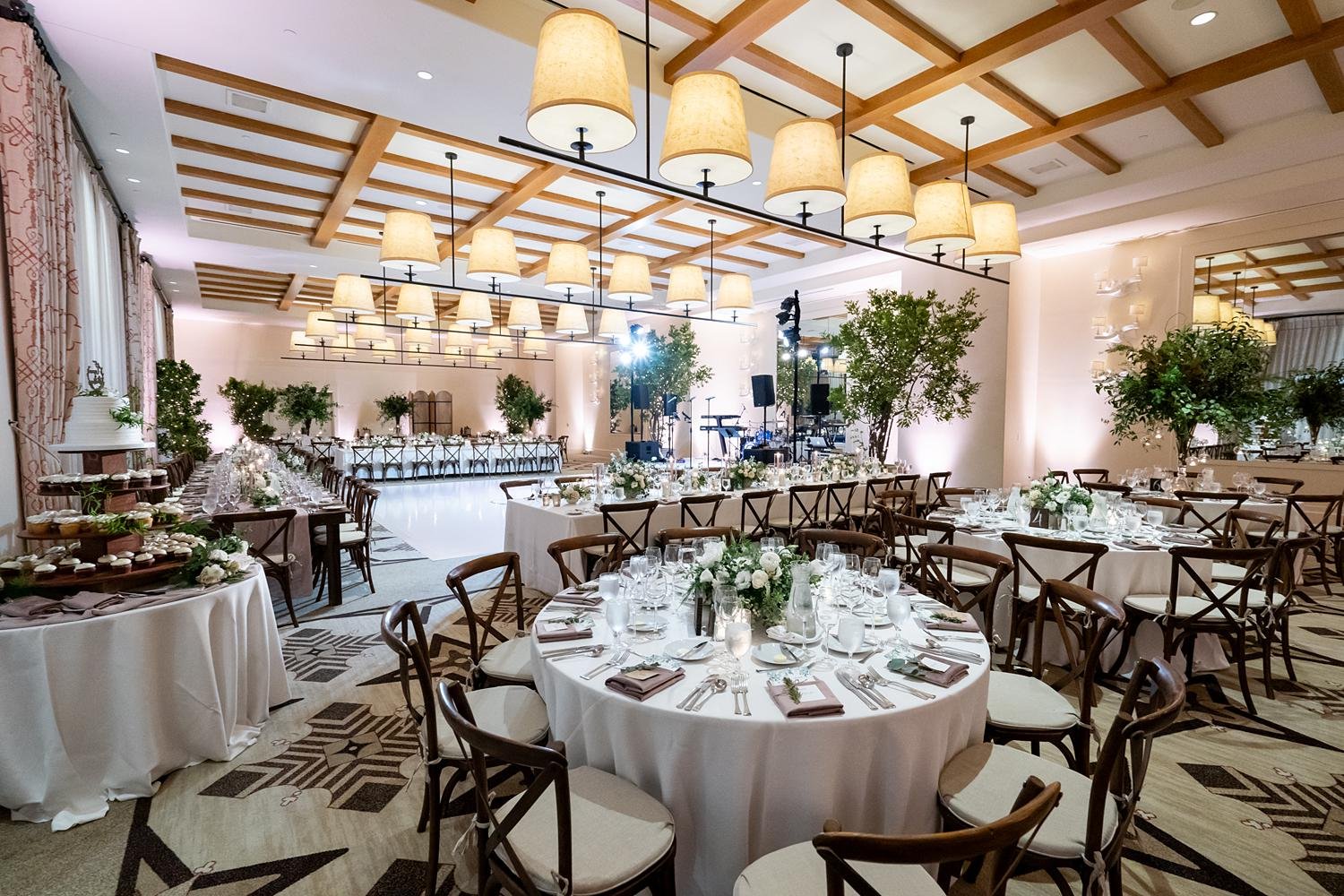 Wedding reception with white florals, greenery, and wooden tables in the Catalina Ballroom at Terranea Resort