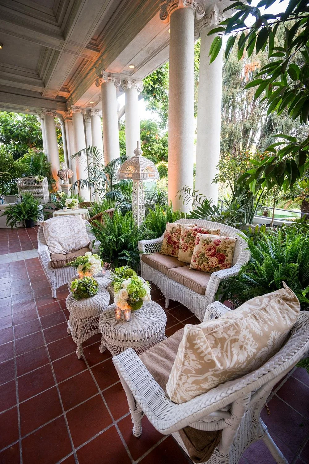 Custom seating area with wicker furniture, pillows and plants at the Estate Patio at a Huntington Library wedding