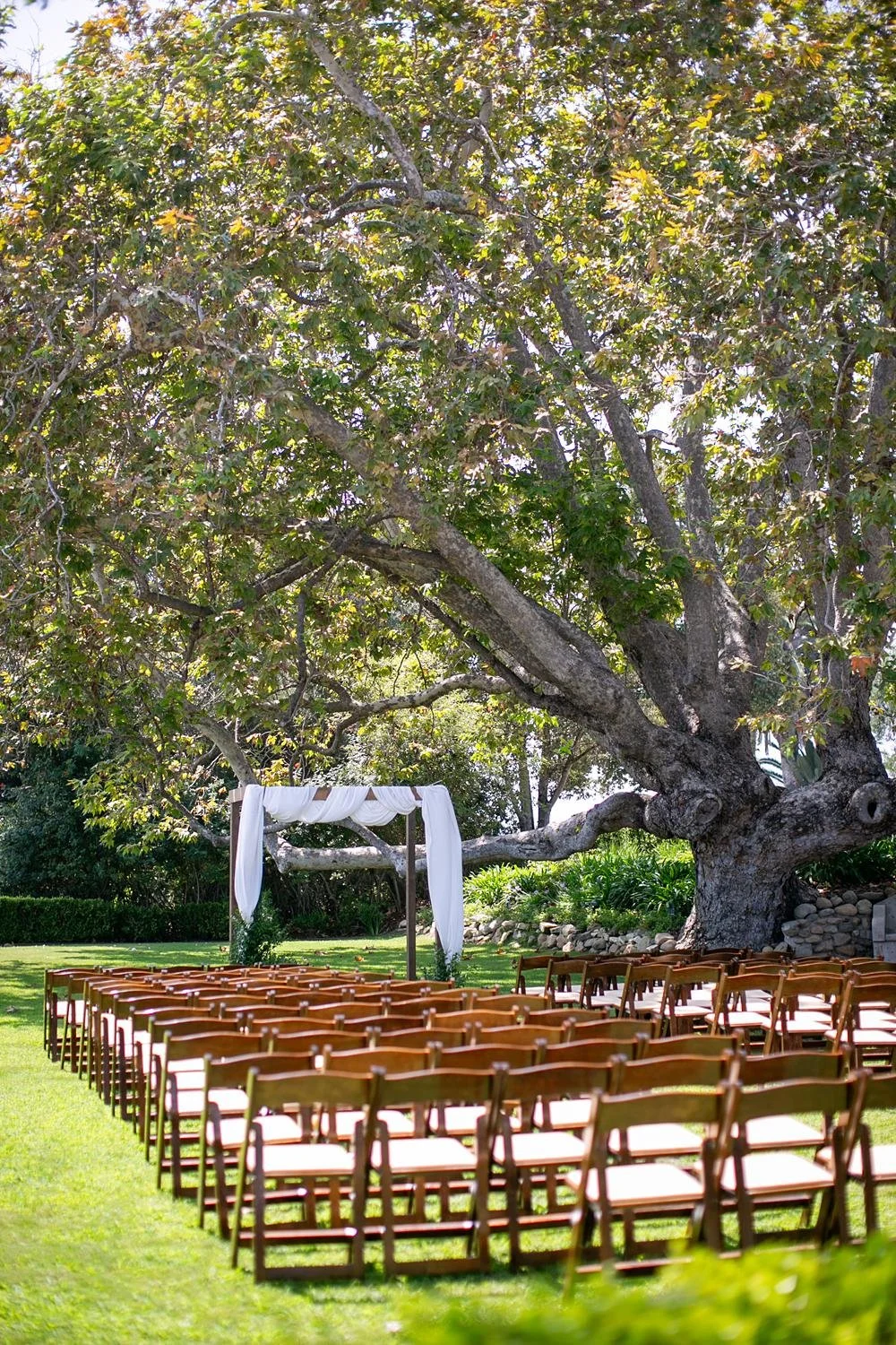 Wedding ceremony at Adamson House on the lawn with a white draped arch