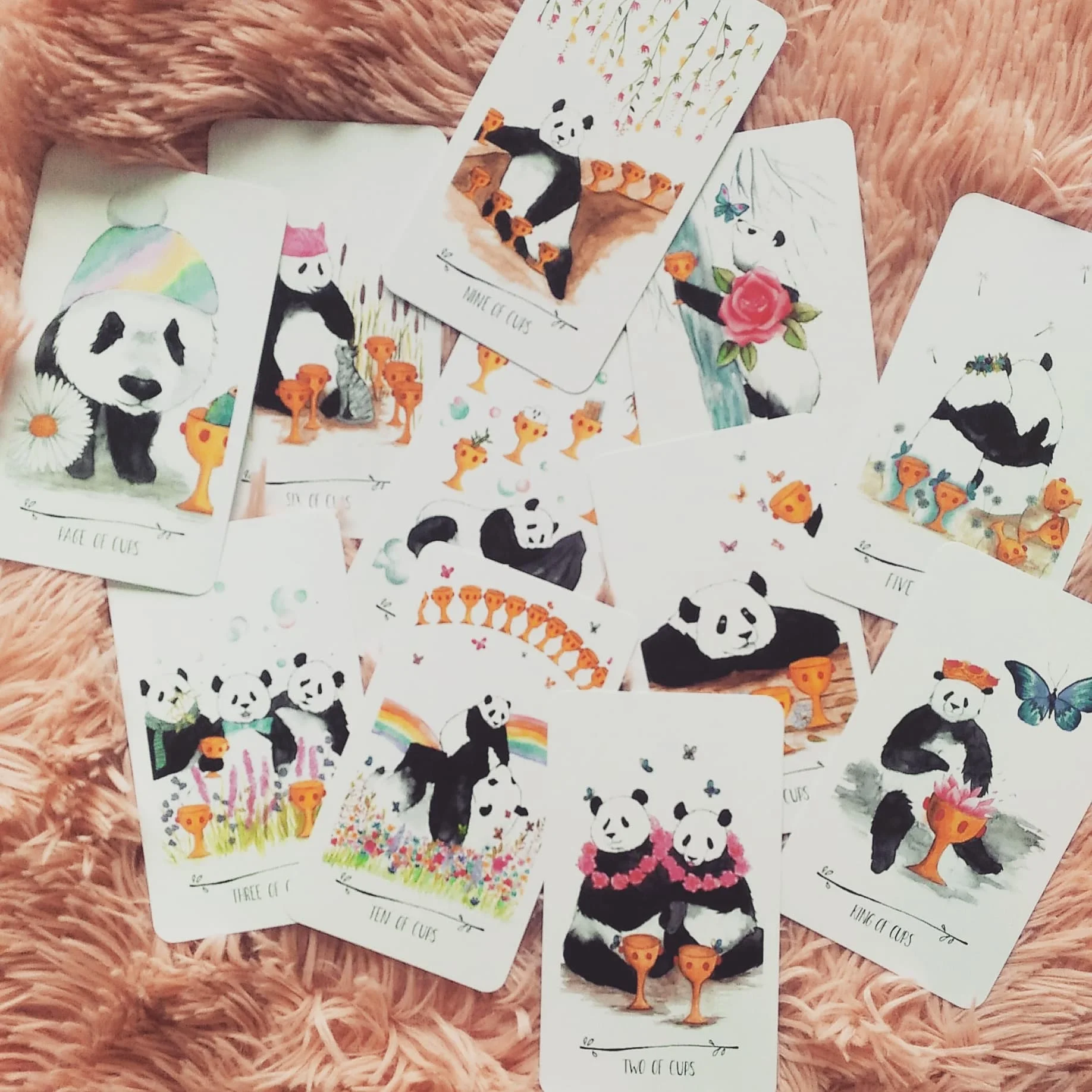 “Suit of Cups” - not all the cards from the Suit of Cups are shown in this picture. The Water Pandas have a special place in my heart (well, all the pandas do, but the Water Pandas are the closest to my heart because I’m a big Water Panda myself). When I first started working with my artist on this suit, I knew there was going to be lots of fauna - flowers, grass, vegetation - it’s like the pandas are going to be surrounded by nature’s sensitivies in the form of gardens and flower bushes. Oh, and also butterflies. They convey tenderness, and the catharsis that we can have when we hold space for our emotions.