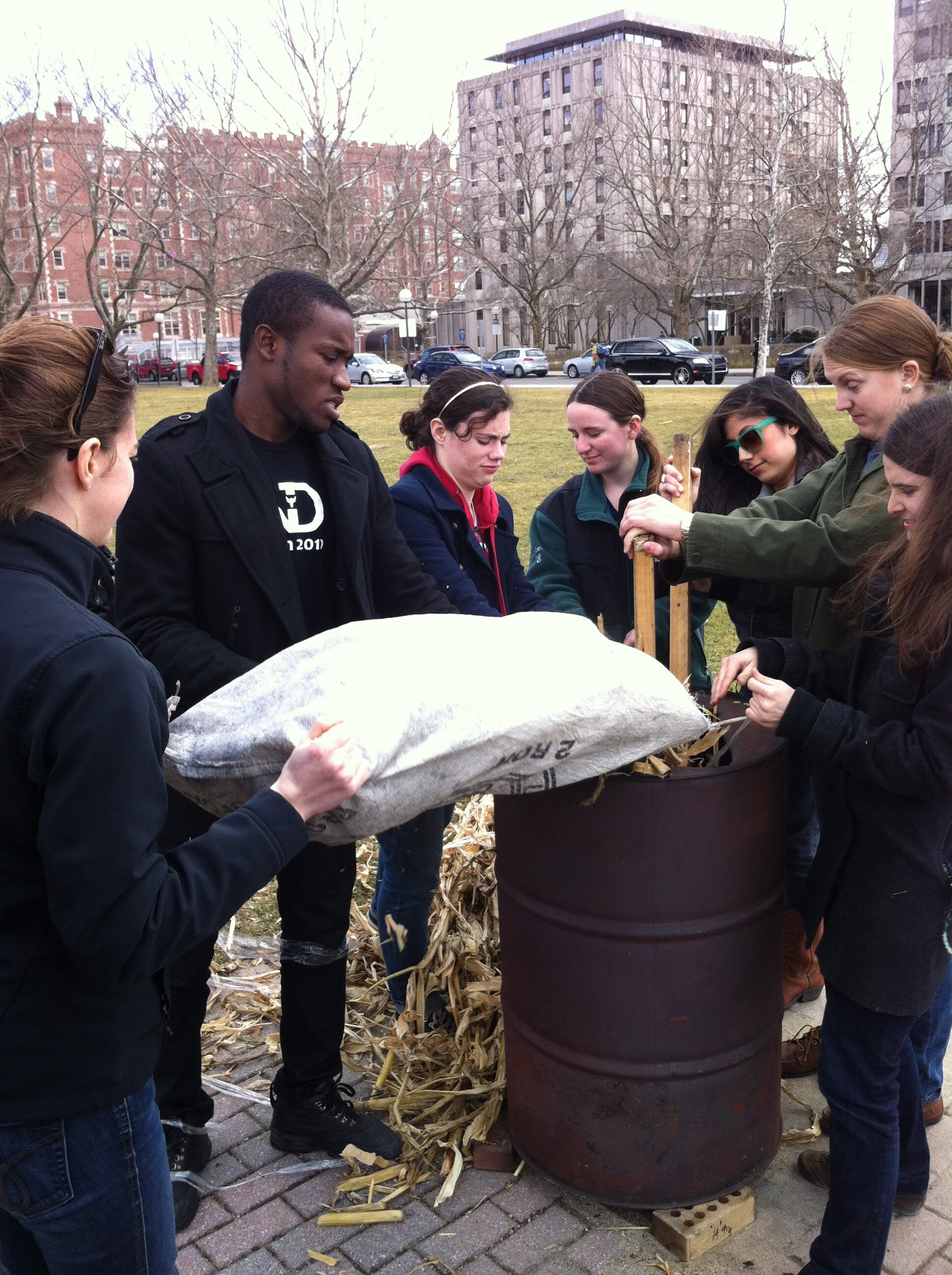 Students Fill a Barrel With Agricultural Waste to Make Charcoal Briquettes for Cooking Fuel