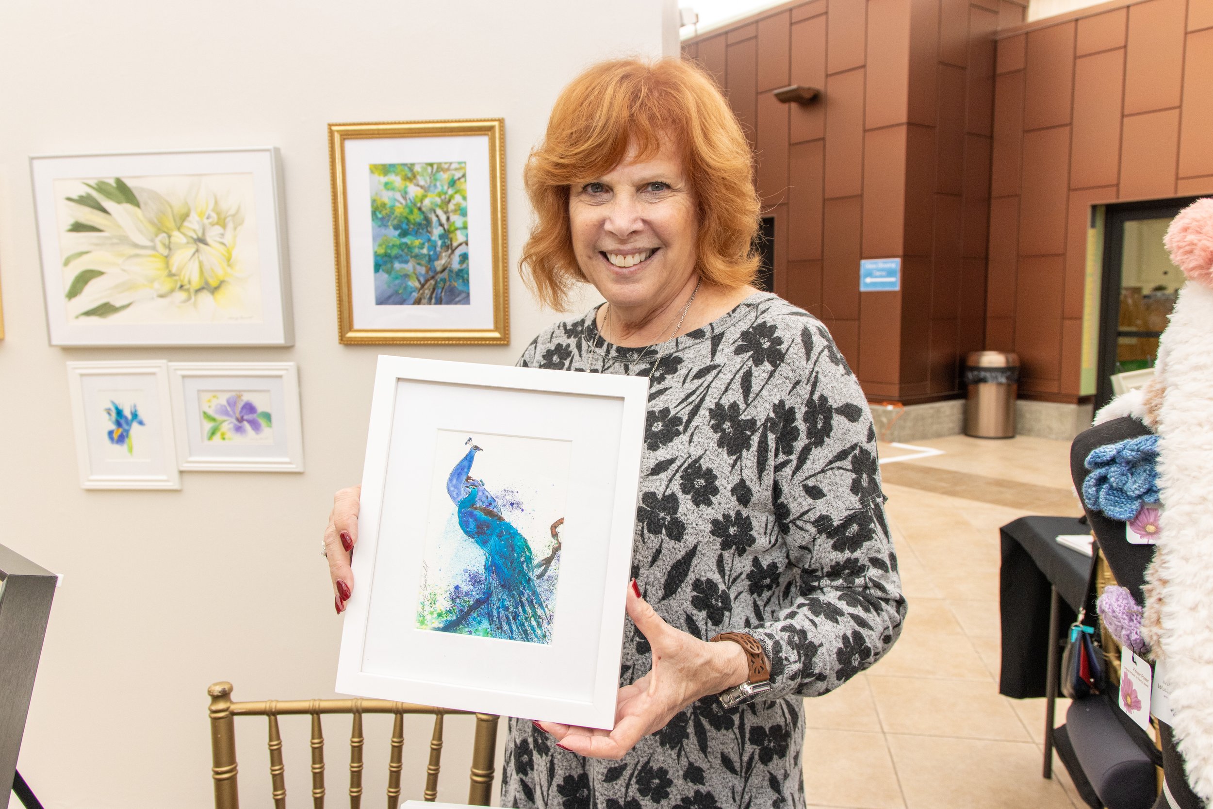 Nancy Sewell holding her watercolor art piece, Peacocks, perfect pair.
