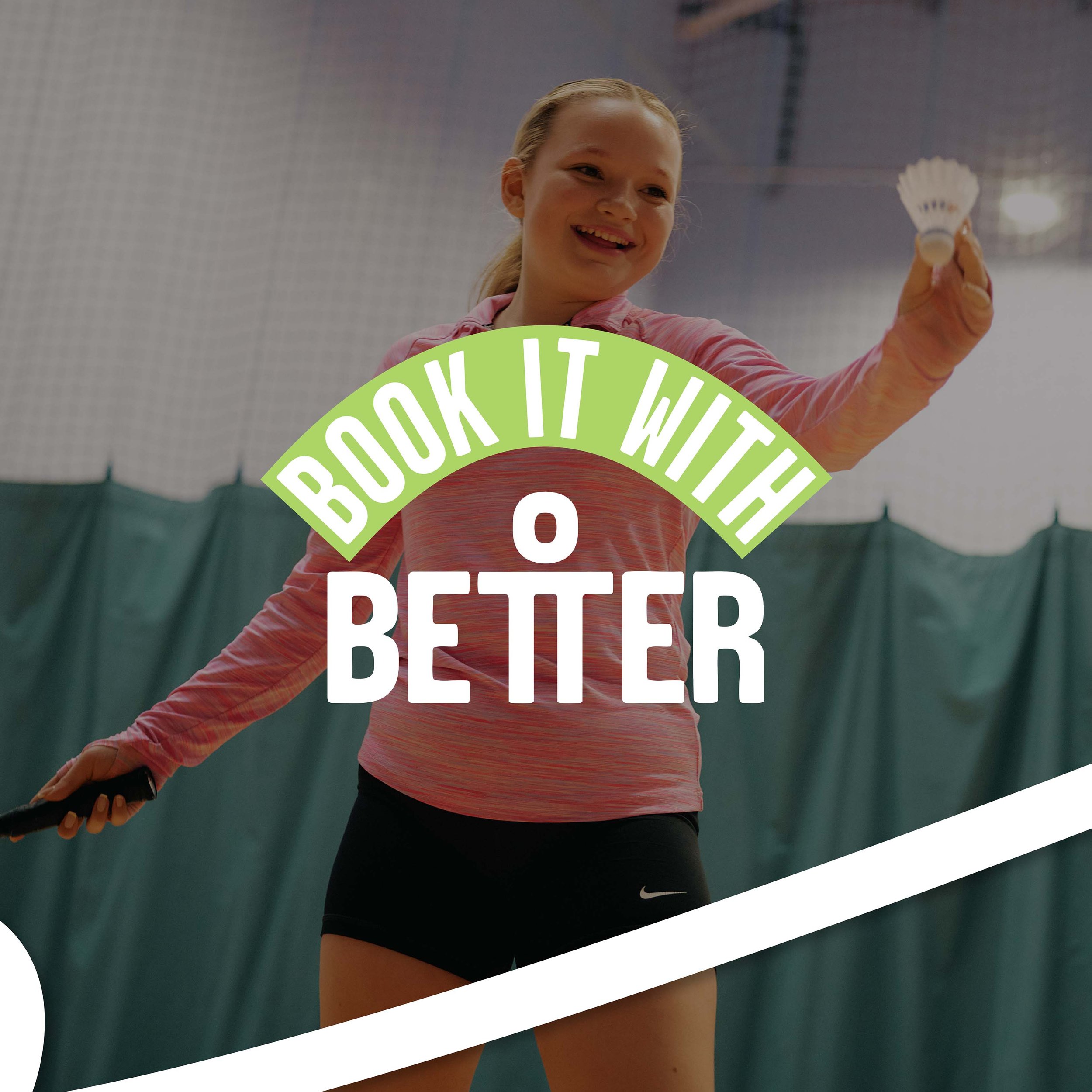 A female tennis player smiling during a match, holding a tennis racquet, wearing a pink shirt and black shorts, standing on a tennis court.