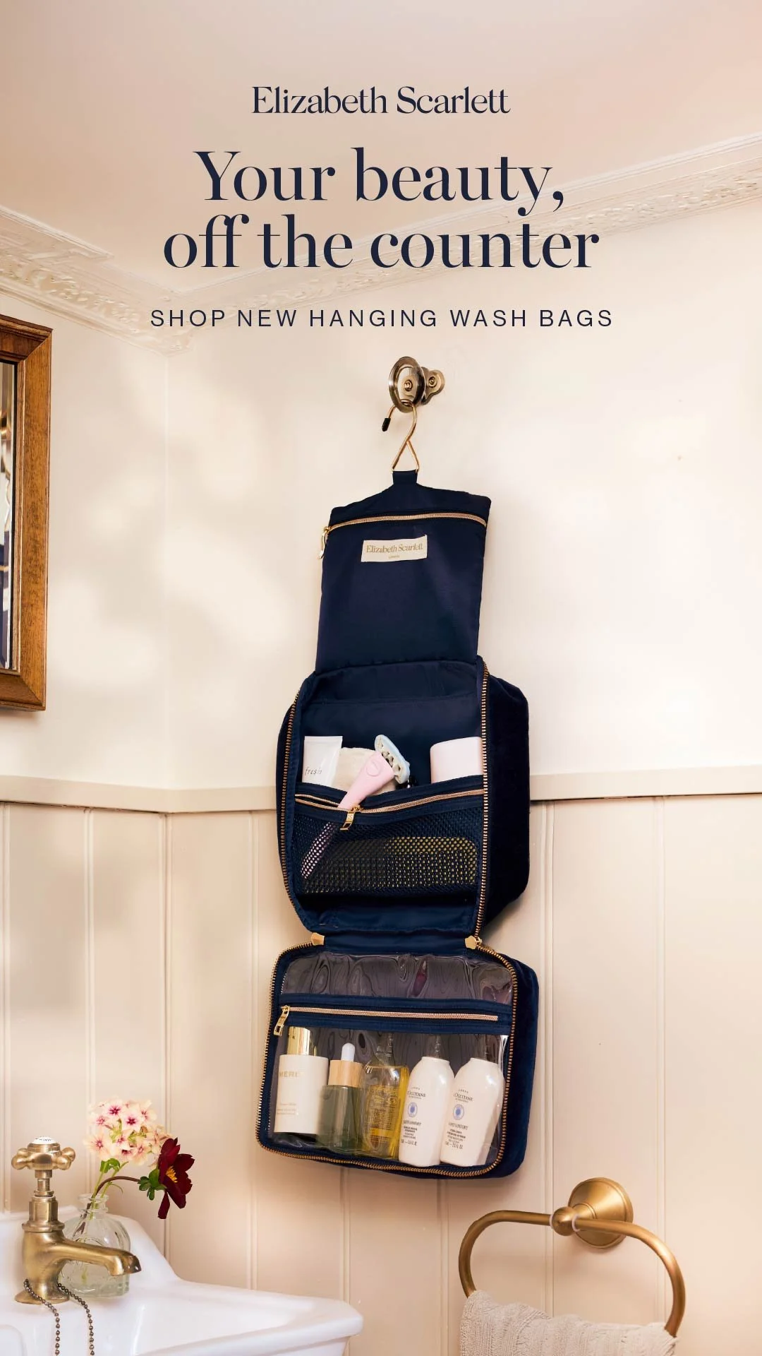 An advertisement for new hanging wash bags by Elizabeth Scarlett on a bathroom wall, with toiletries and a sink below.