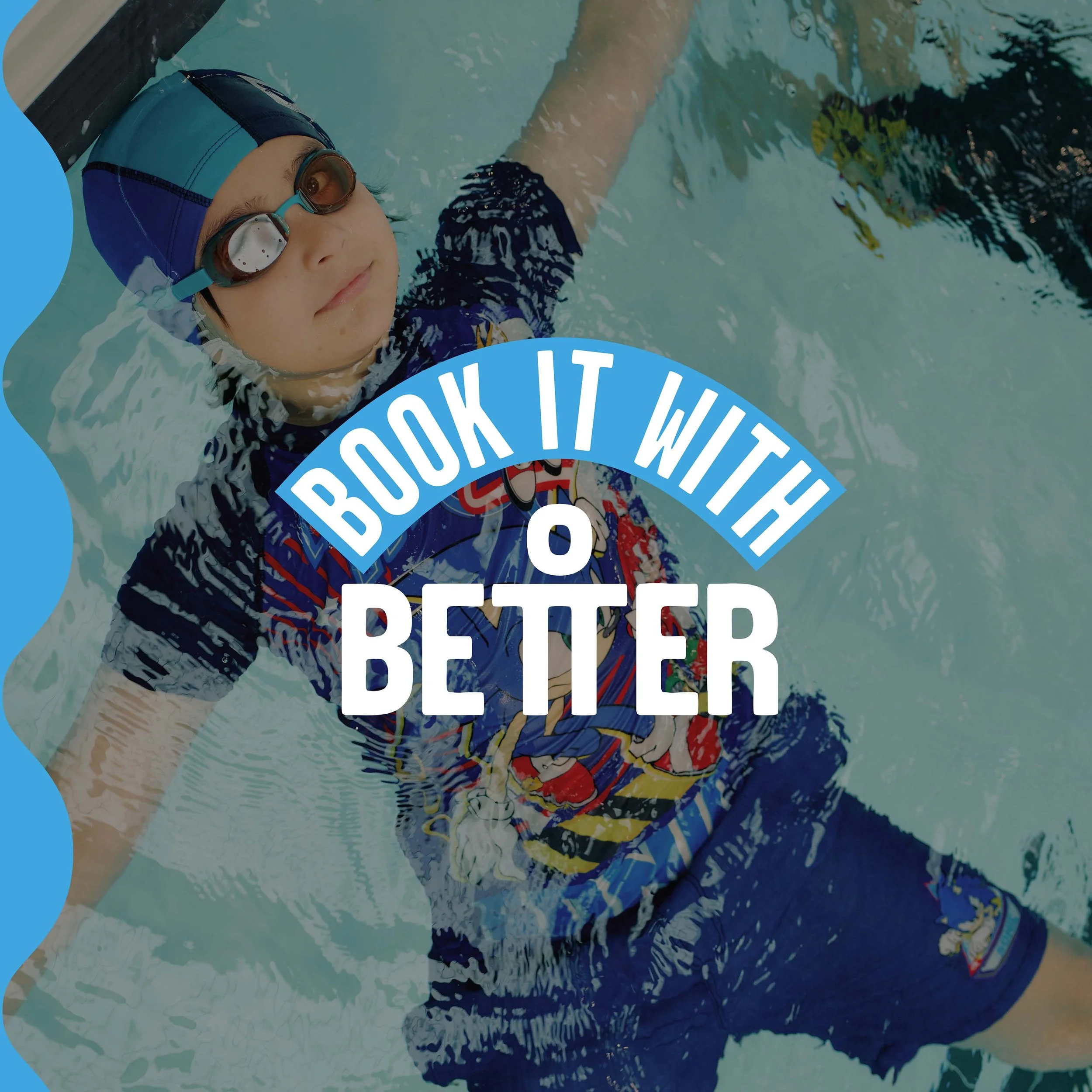 A young boy swimming in a pool, wearing swim goggles, a swim cap, and a shirt with a graphic design. The boy is holding an underwater toy or object.