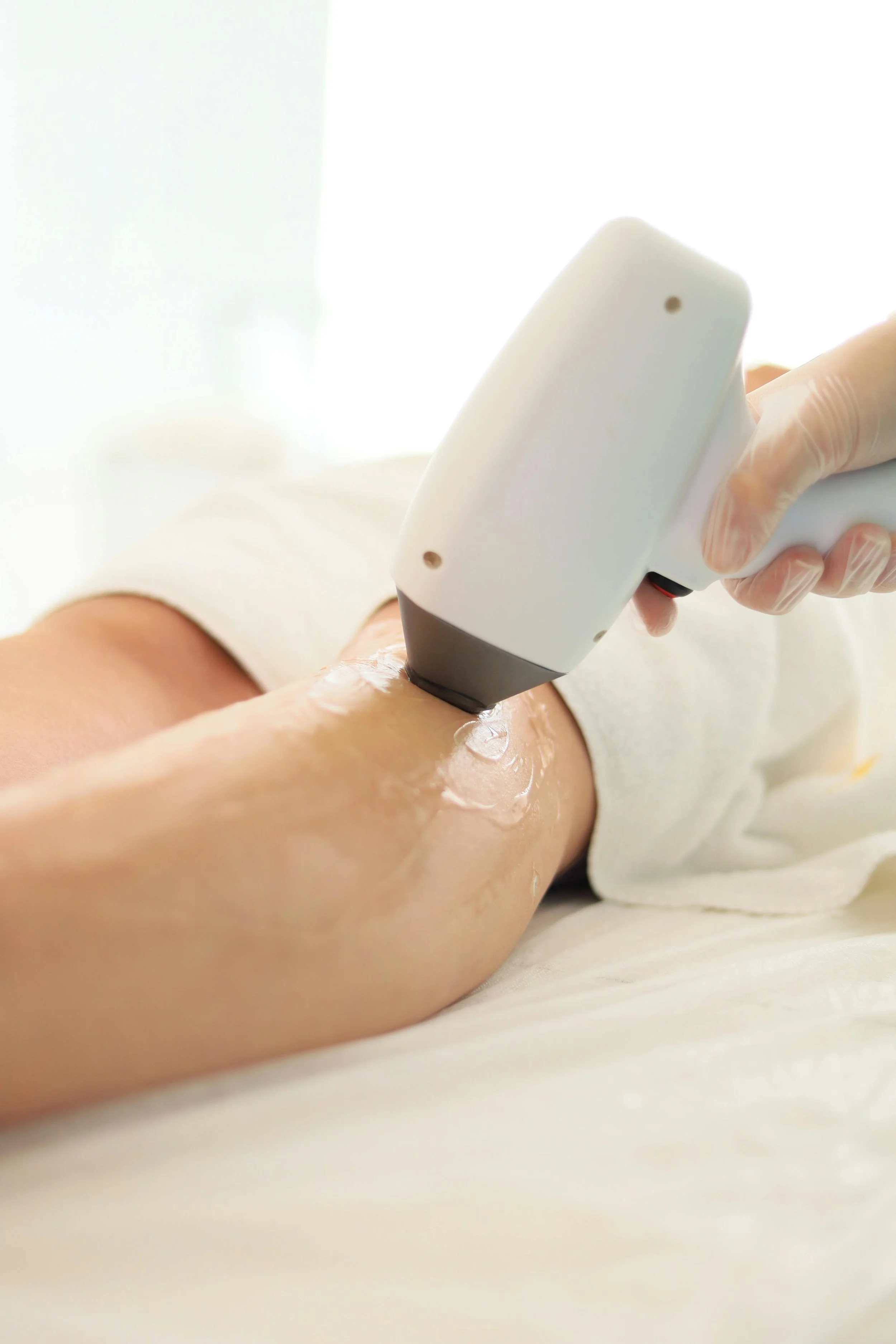 A person holding a laser hair removal device and applying it to their leg